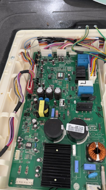 Interior of an electronic device with a green circuit board, wires, capacitors, and a black heatsink.