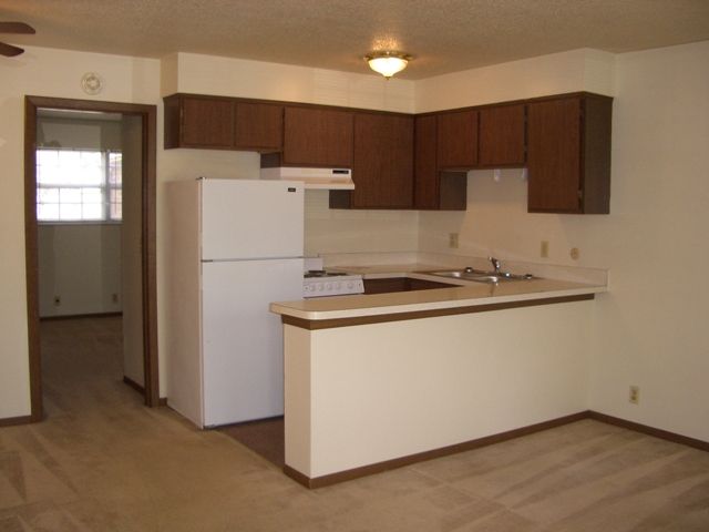 A kitchen with brown cabinets and a white refrigerator