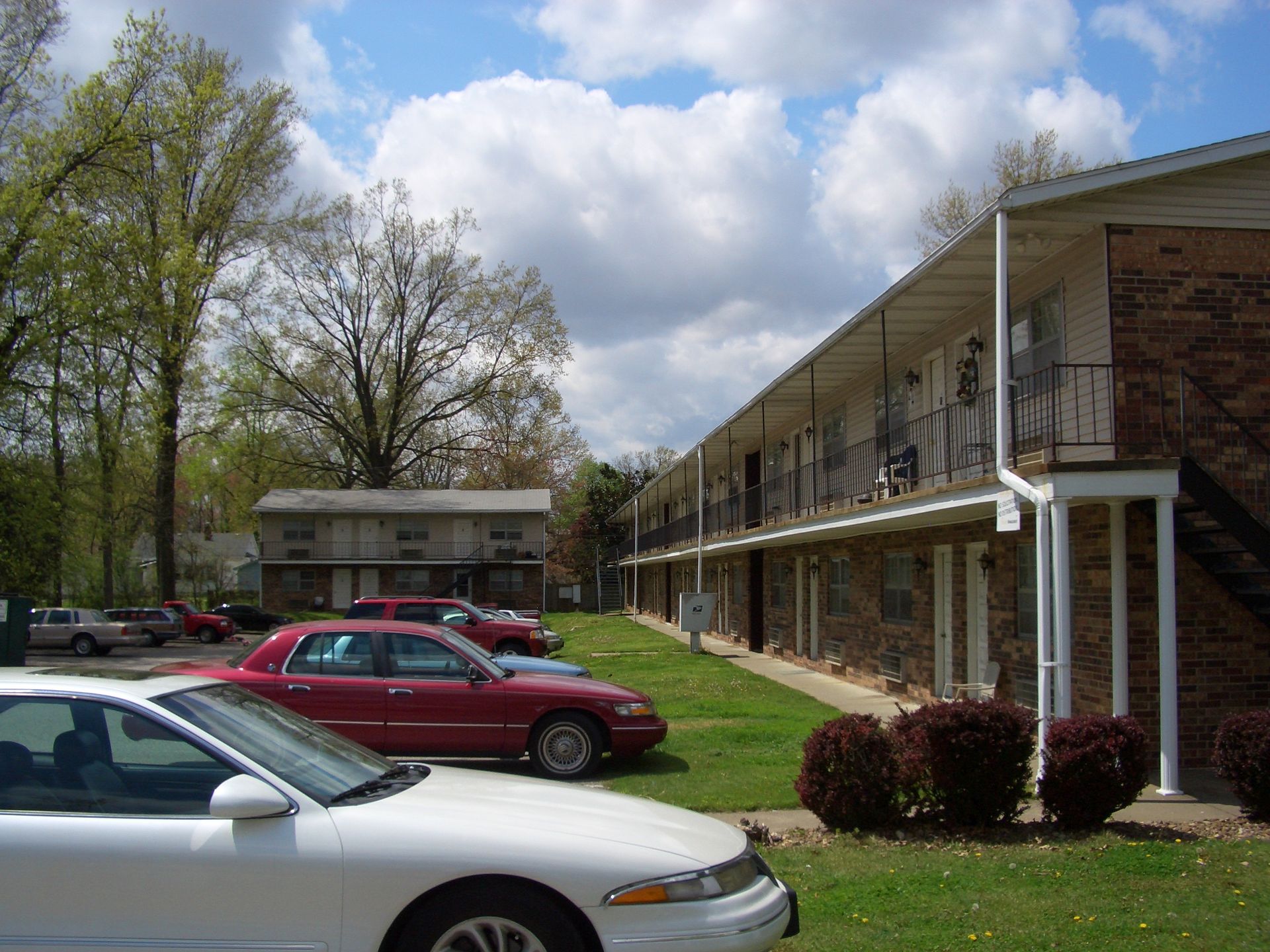 A white car is parked in front of a brick apartment building