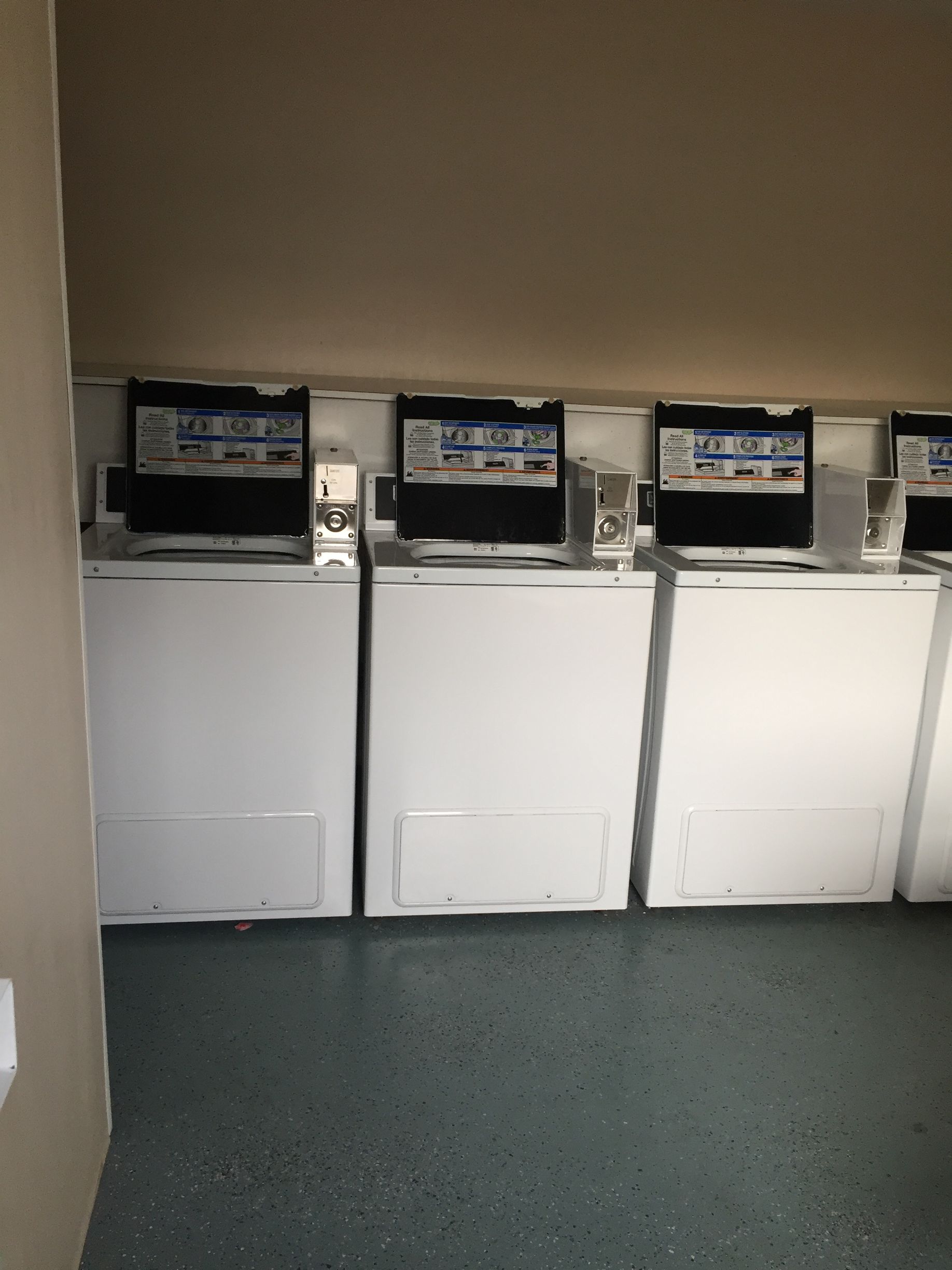 A row of white washers and dryers in a laundromat