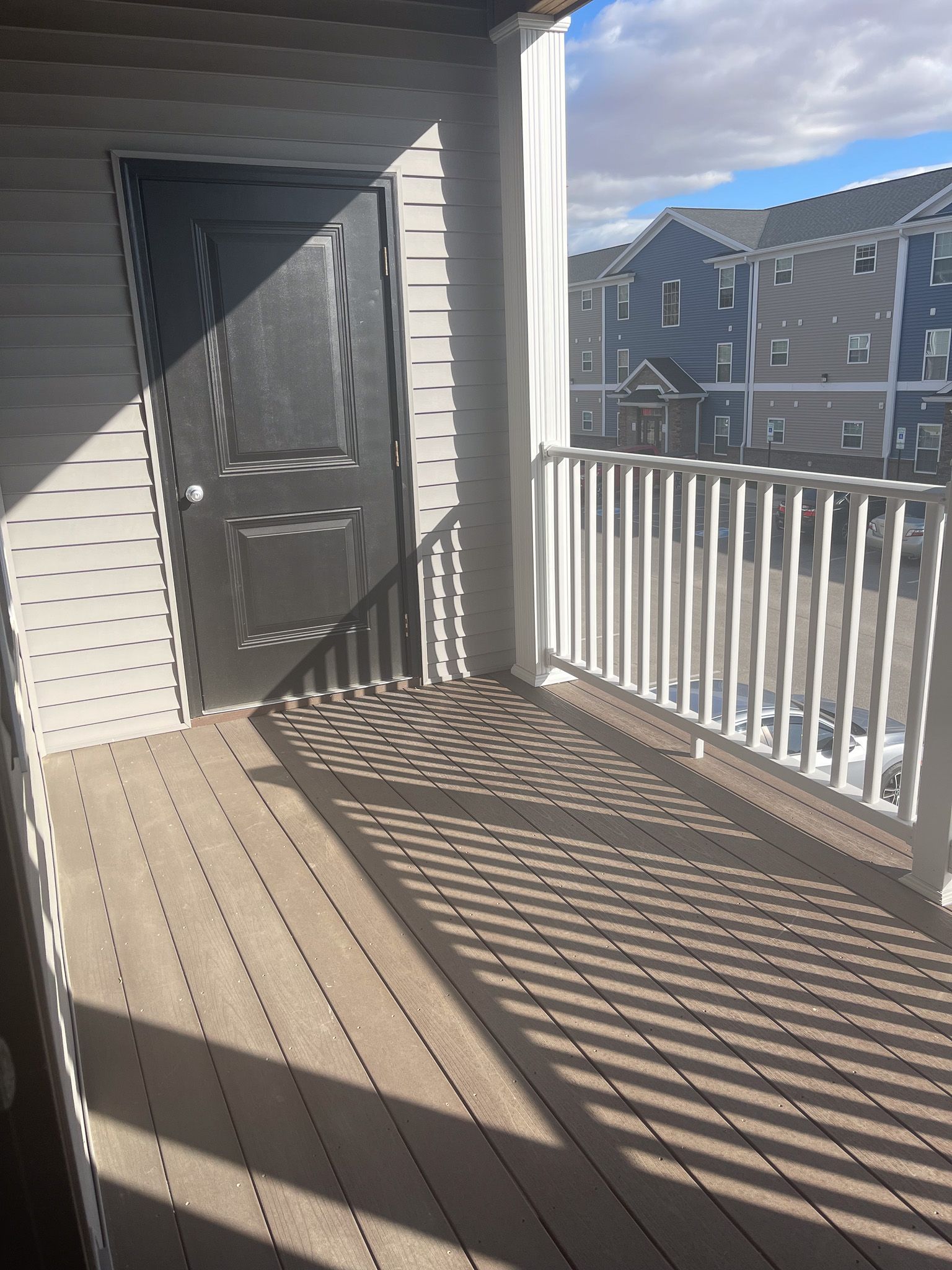 A balcony with a white railing and a black door