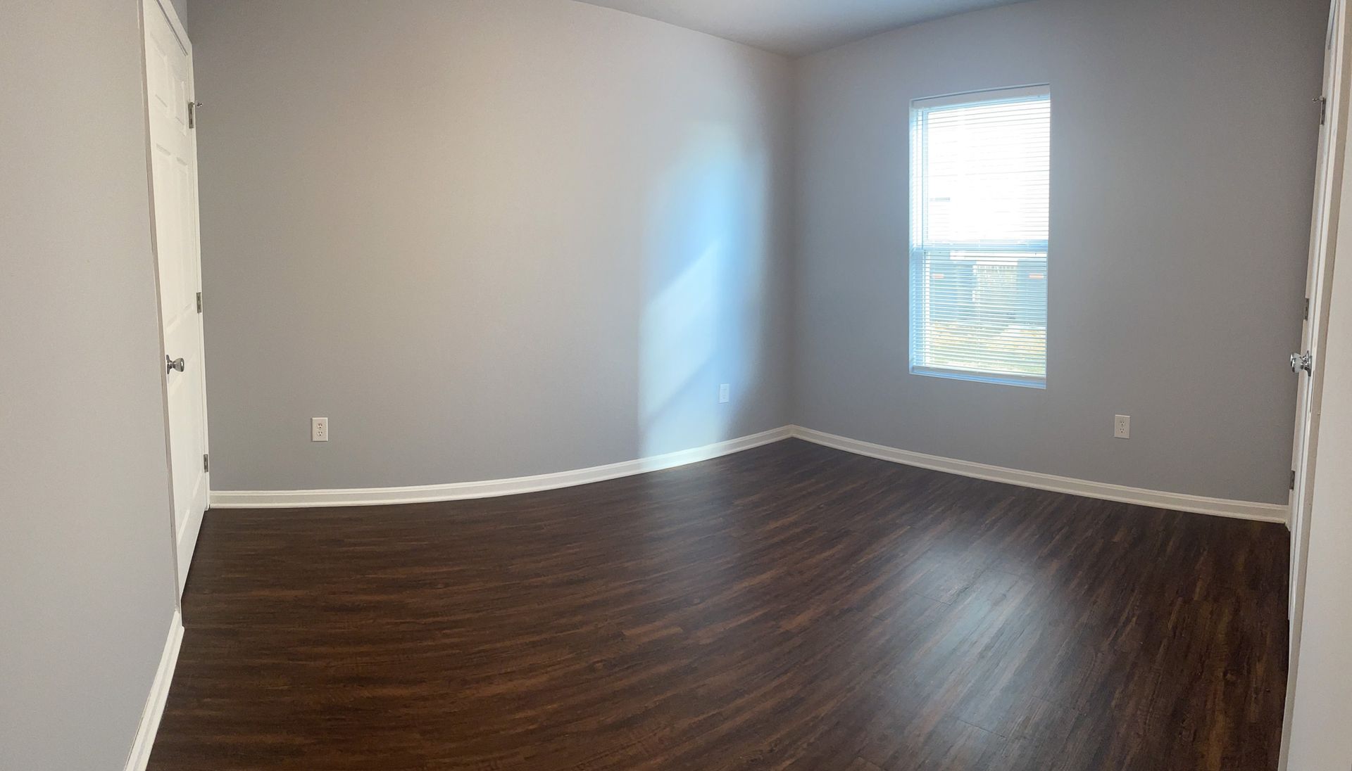 An empty bedroom with hardwood floors and a window.