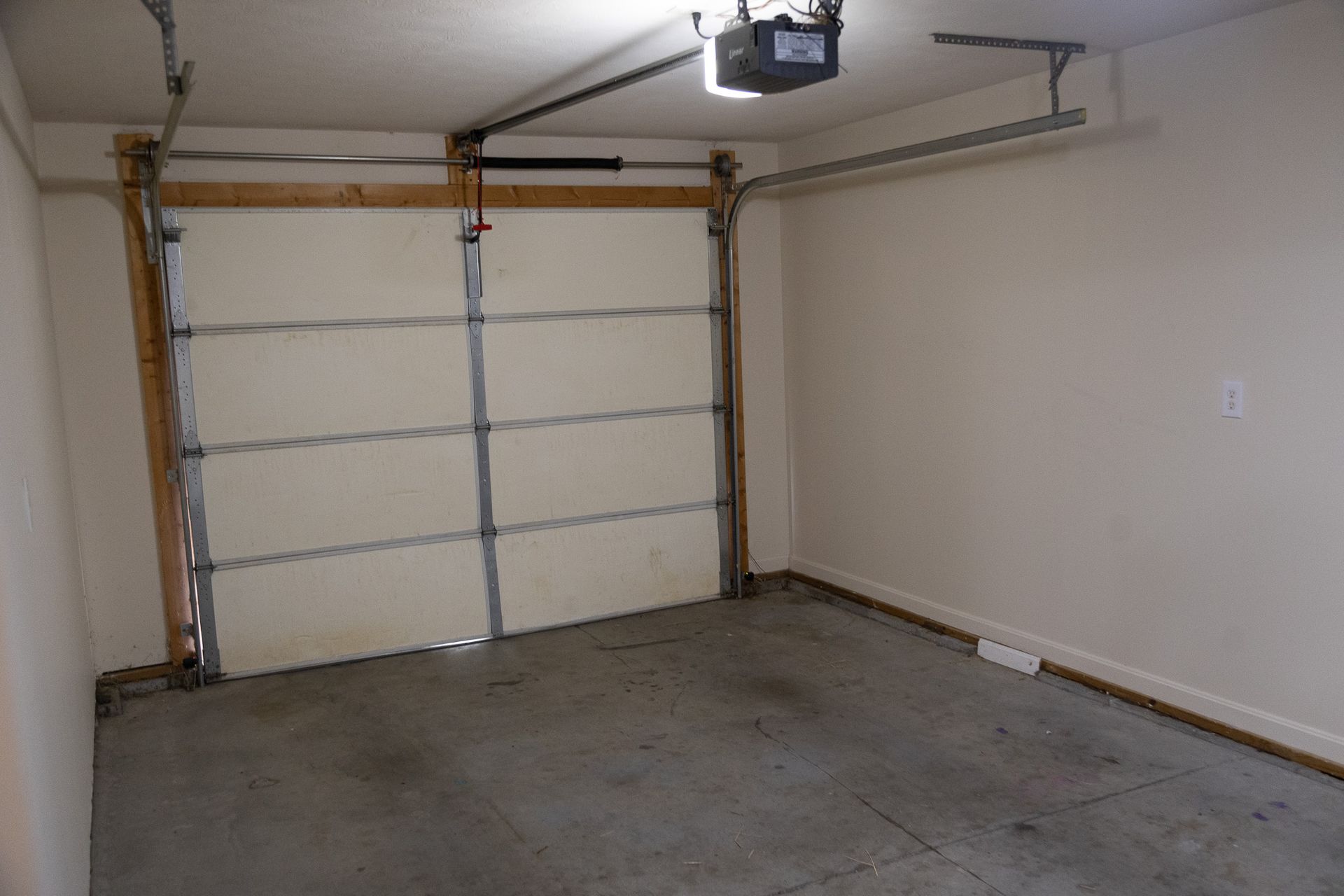 An empty garage with a garage door open and a garage door opener.