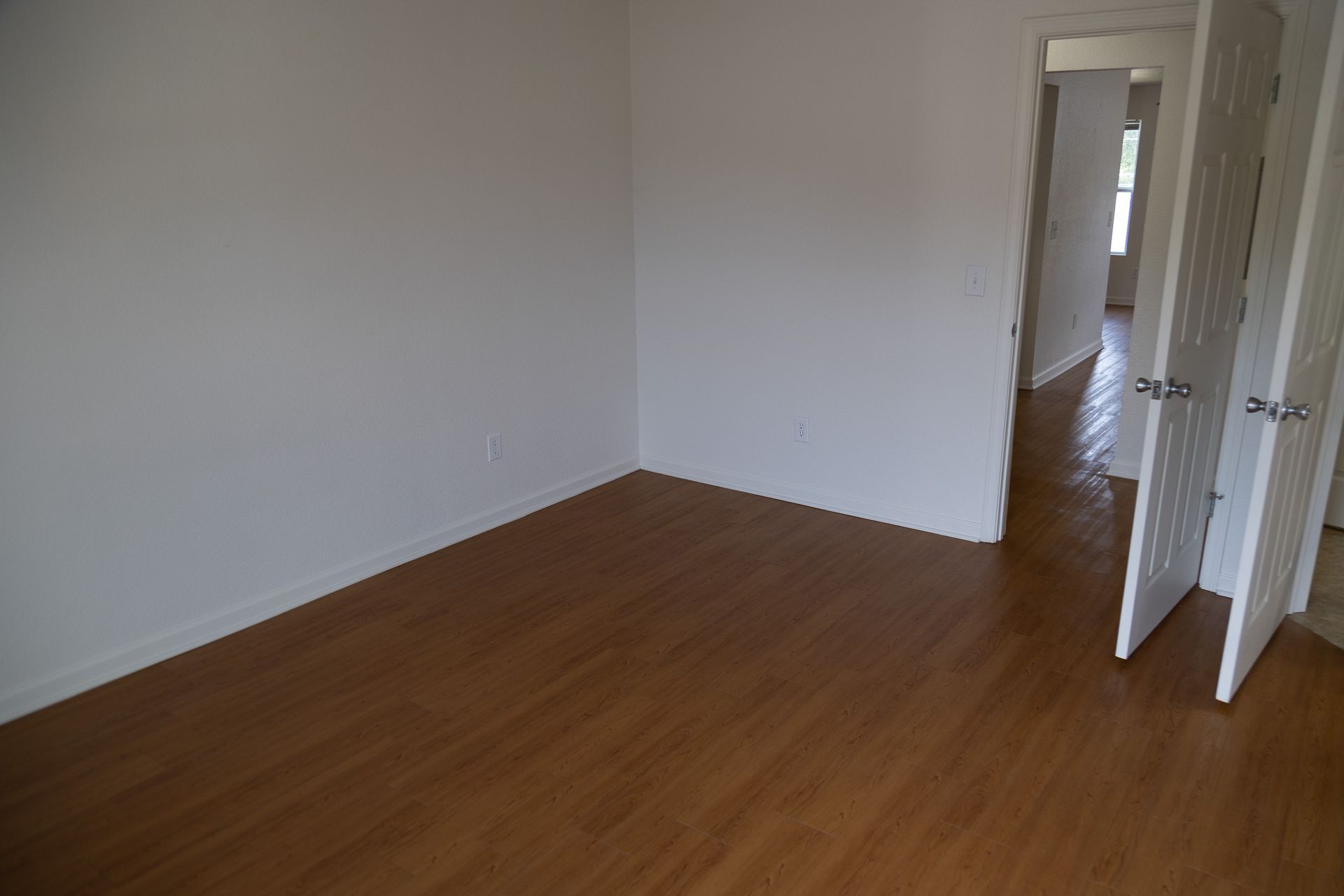 An empty room with hardwood floors and white walls.
