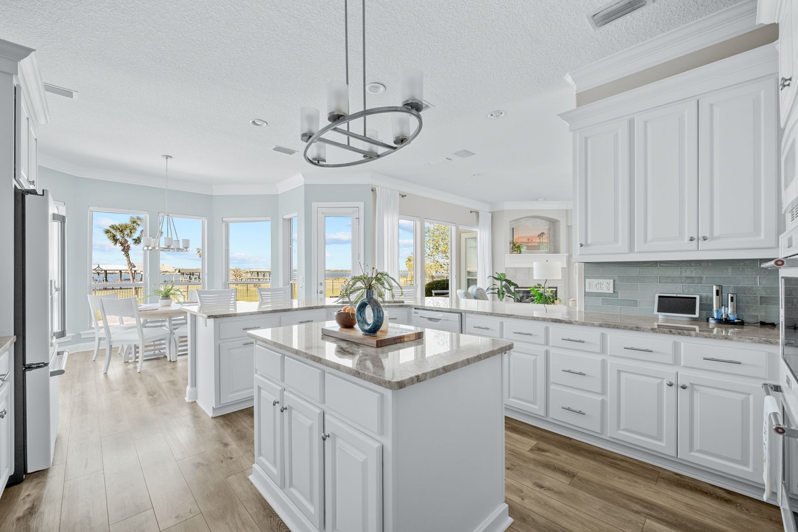 A kitchen with white cabinets , granite counter tops , and a large island.