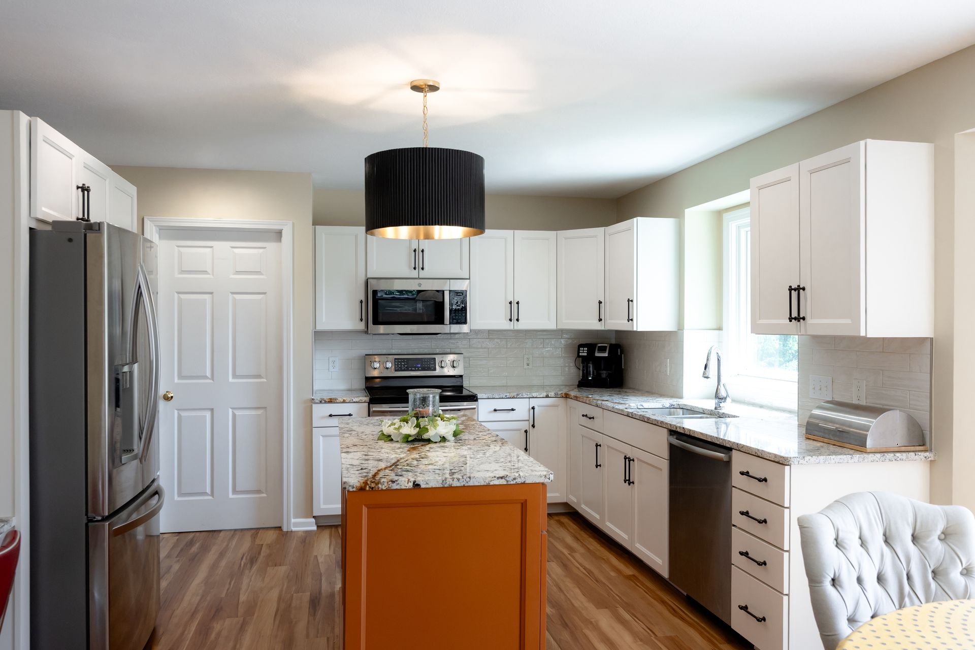 A white kitchen with an orange island.