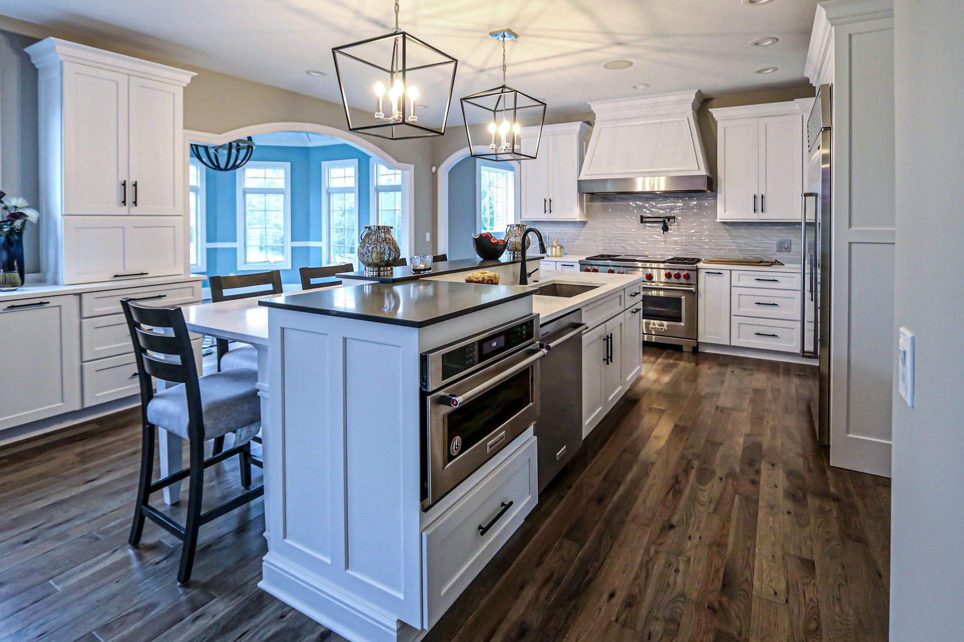A kitchen with white cabinets and stainless steel appliances and a large island in the middle.