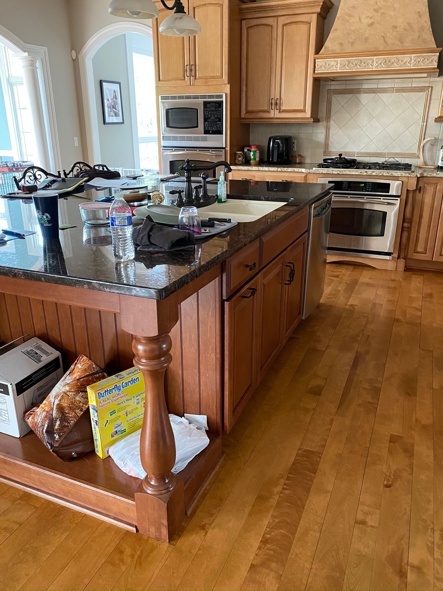 A kitchen with wooden cabinets , granite counter tops , stainless steel appliances and a large island.