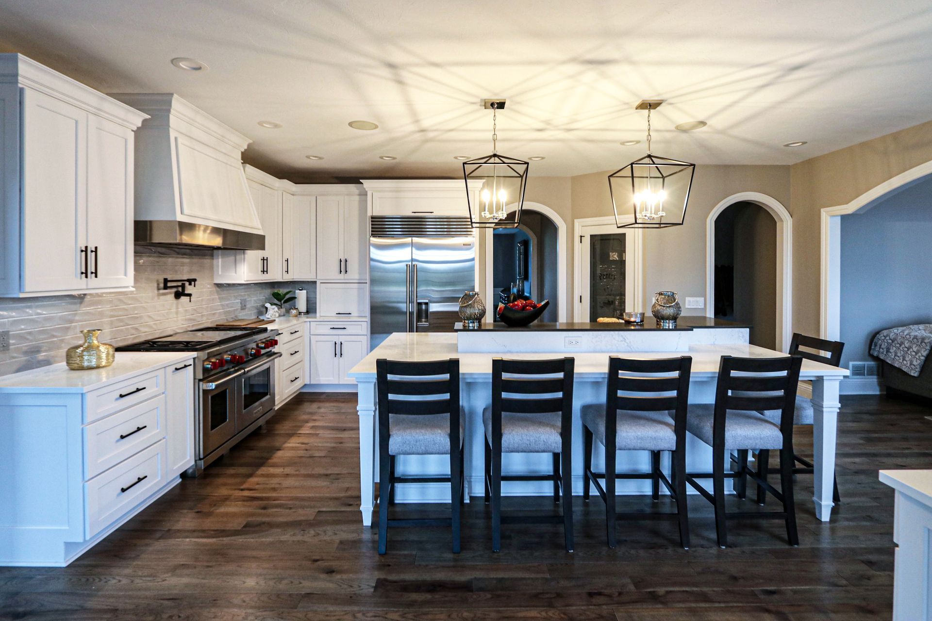 A kitchen with white cabinets and stainless steel appliances and a large island.