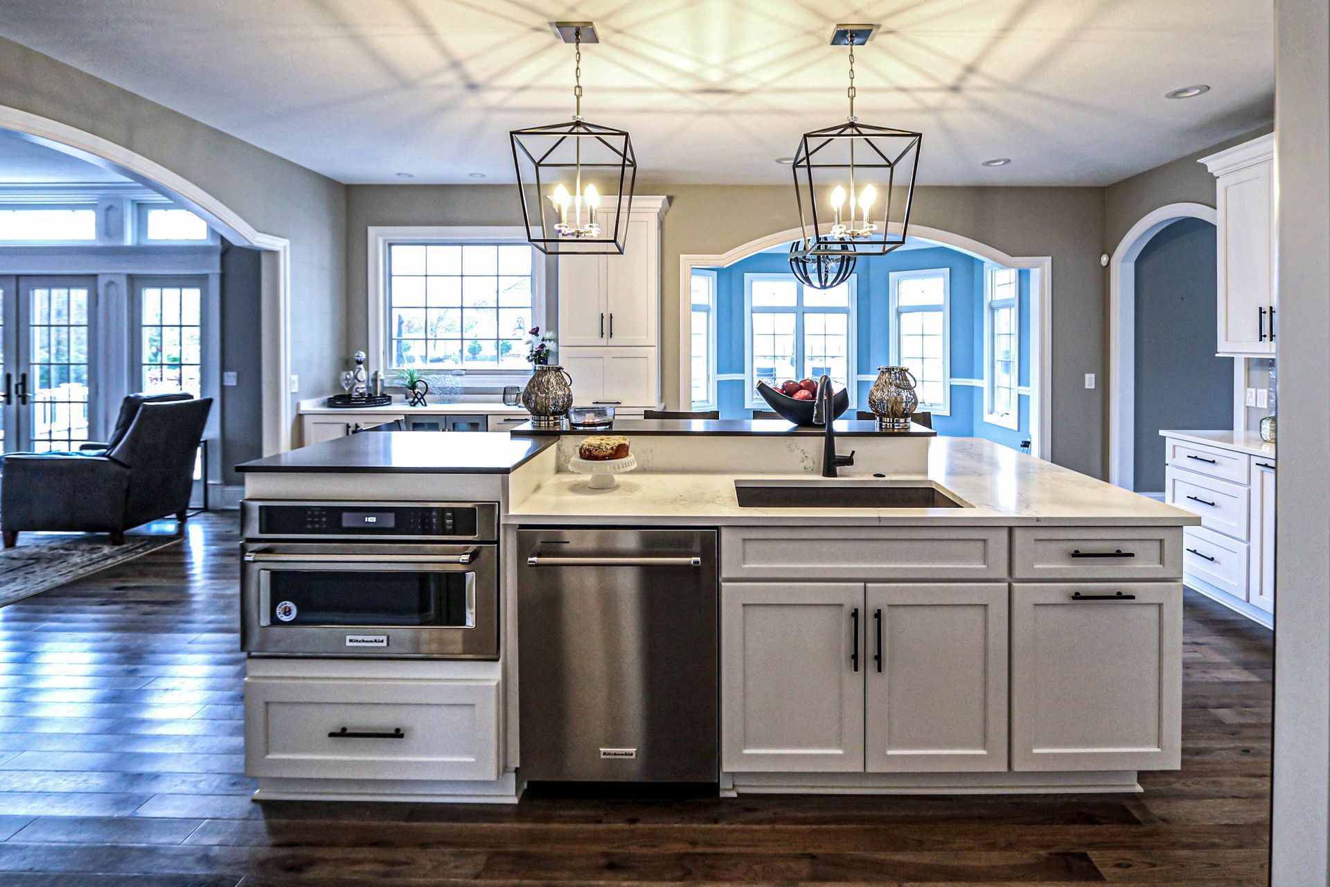 A kitchen with white cabinets , stainless steel appliances , and a large island.