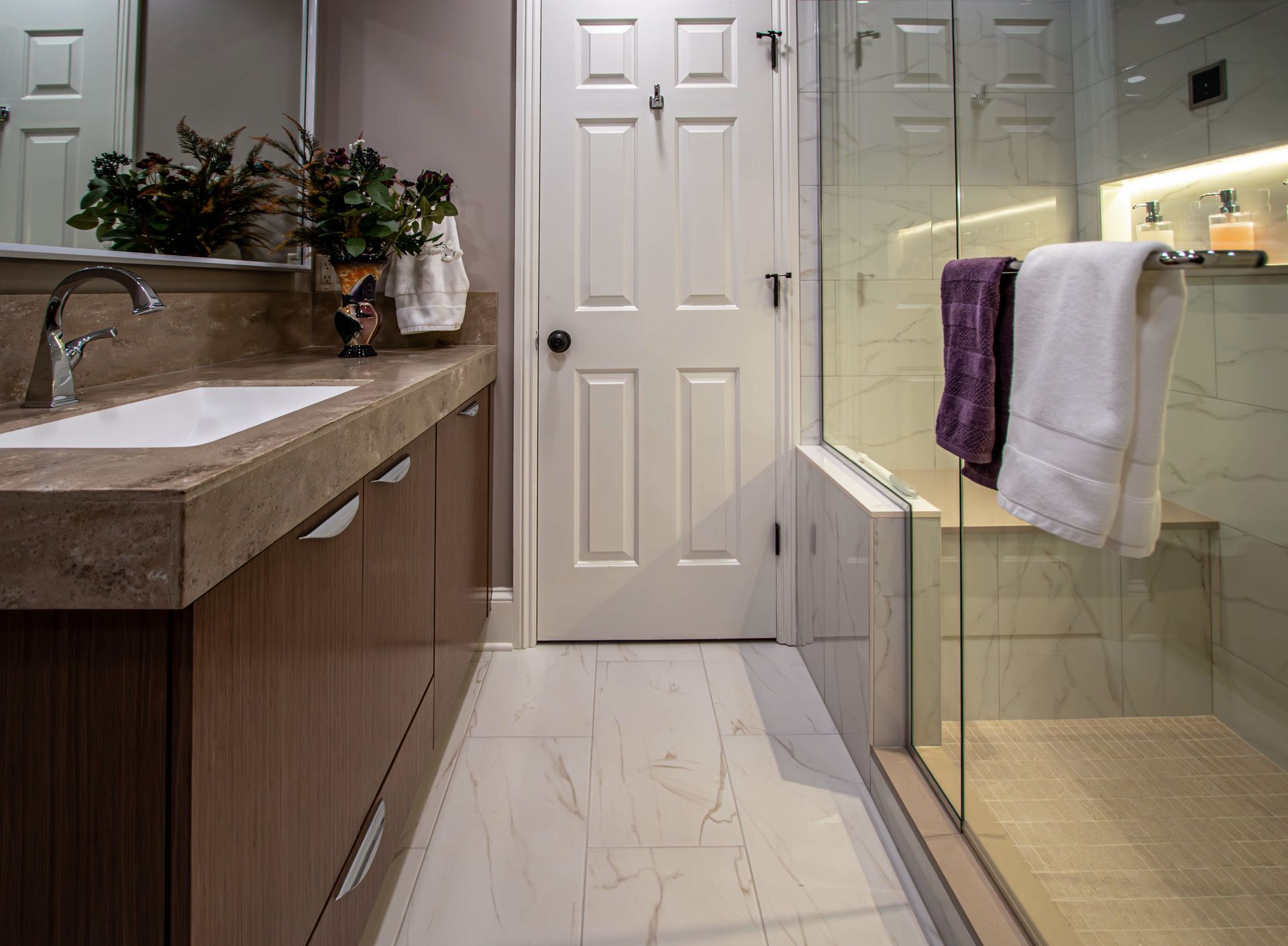 A bathroom with a sink , mirror and walk in shower.