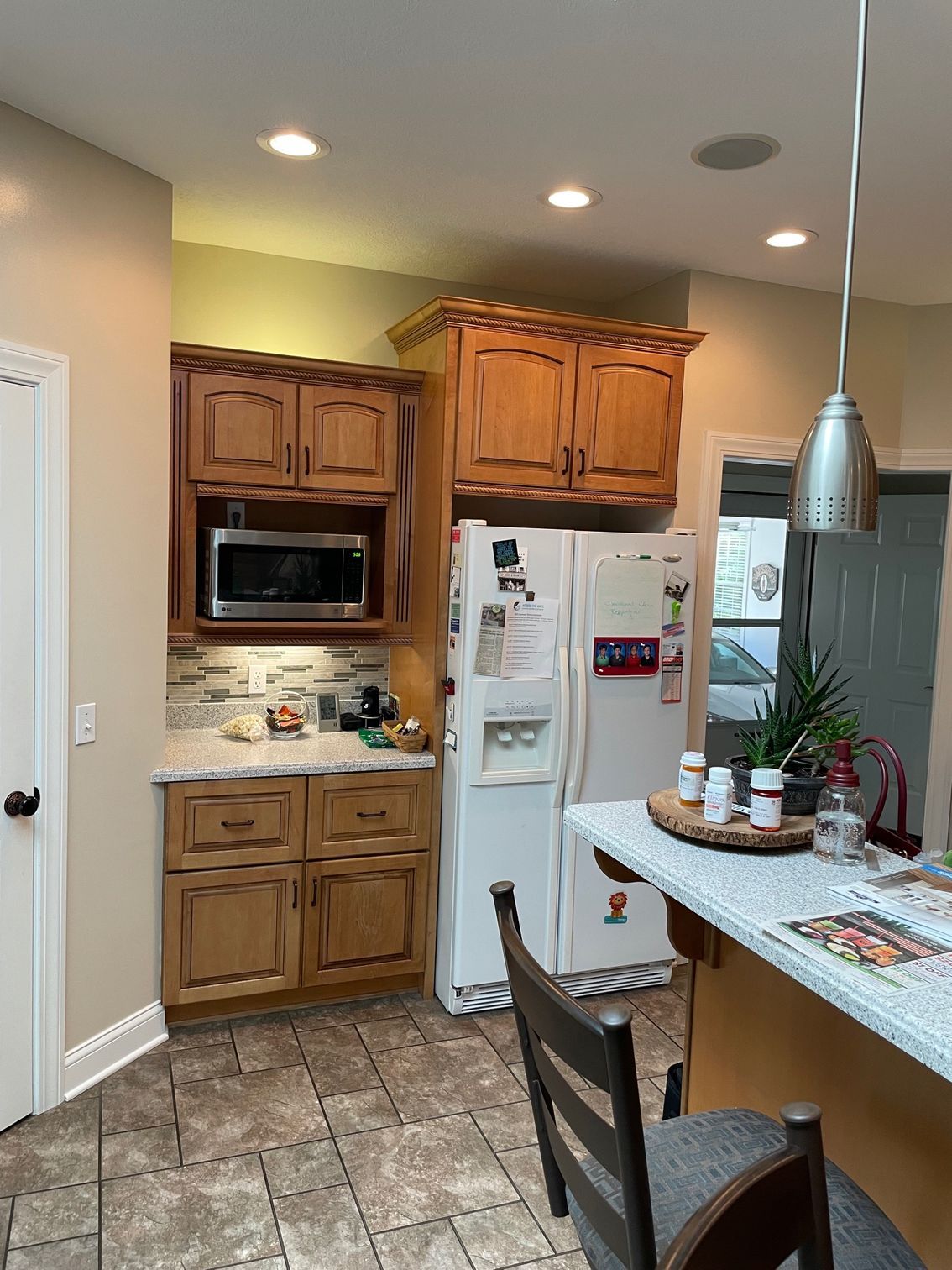 A kitchen with wooden cabinets , a refrigerator , a microwave , and a sink.