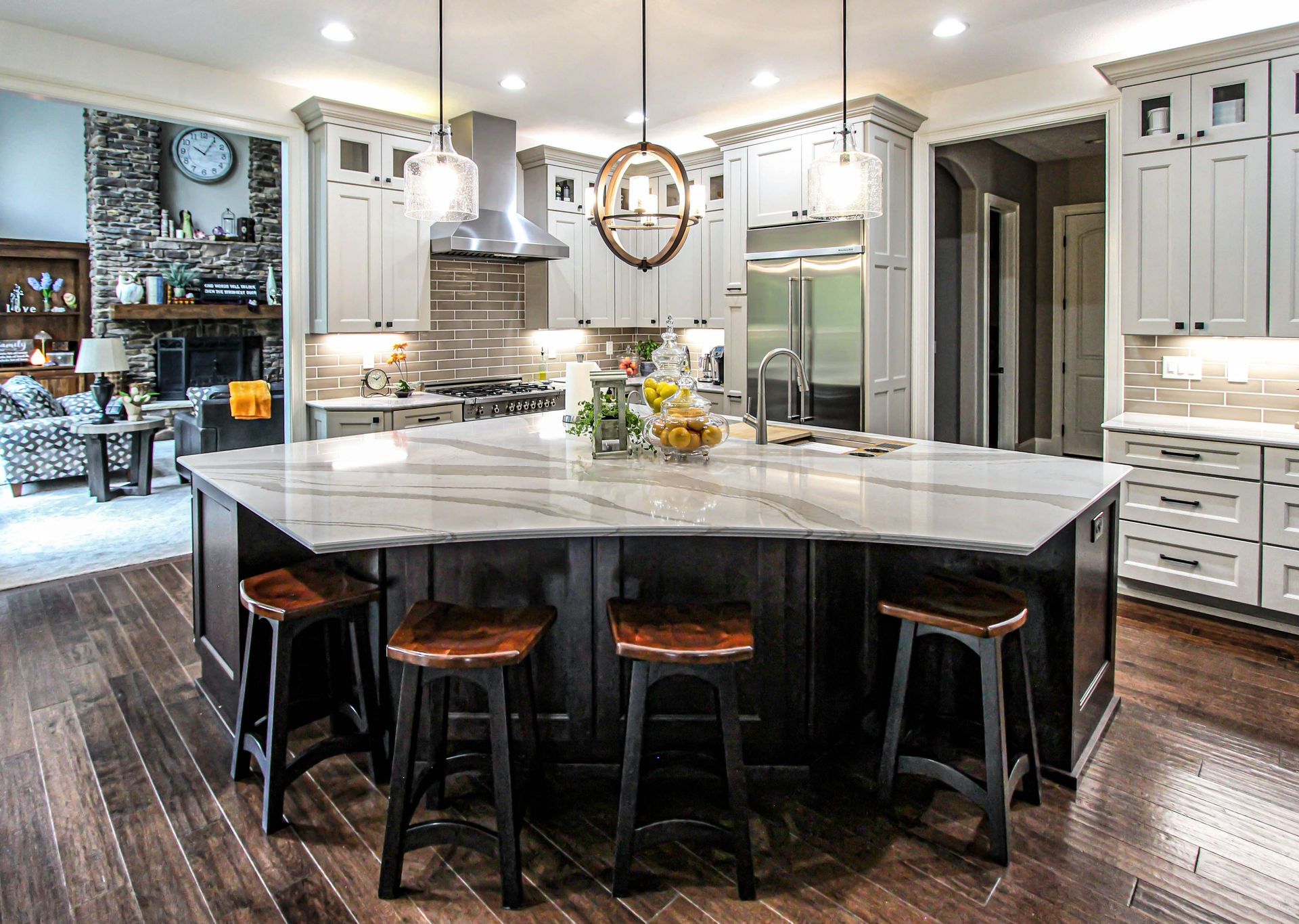 A kitchen with a large island and stools in it.