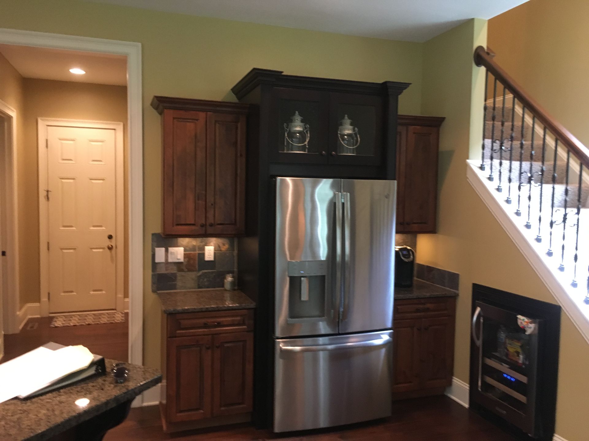 A kitchen with a stainless steel refrigerator and stairs