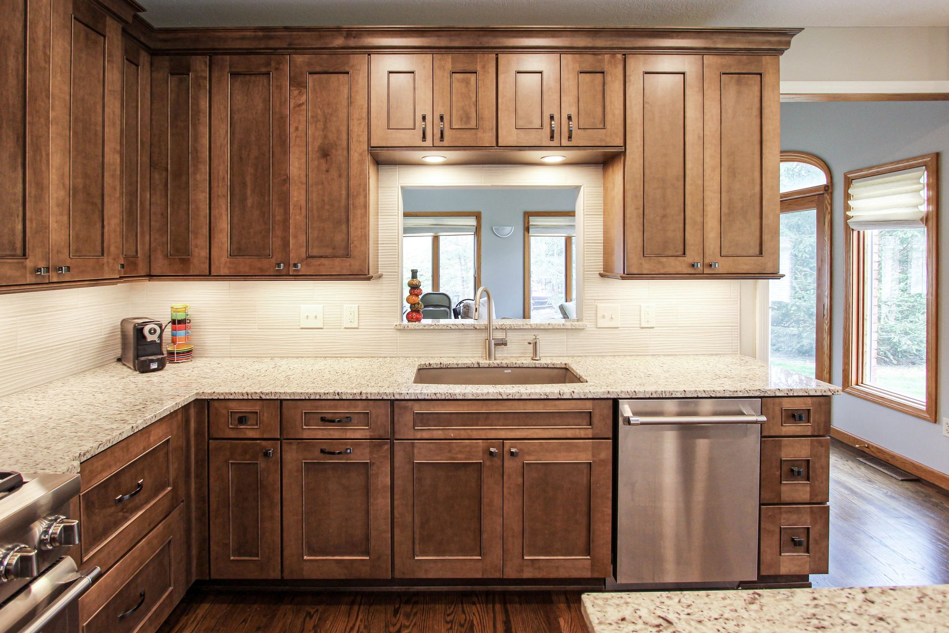 A kitchen with wooden cabinets , granite counter tops , stainless steel appliances and a sink.