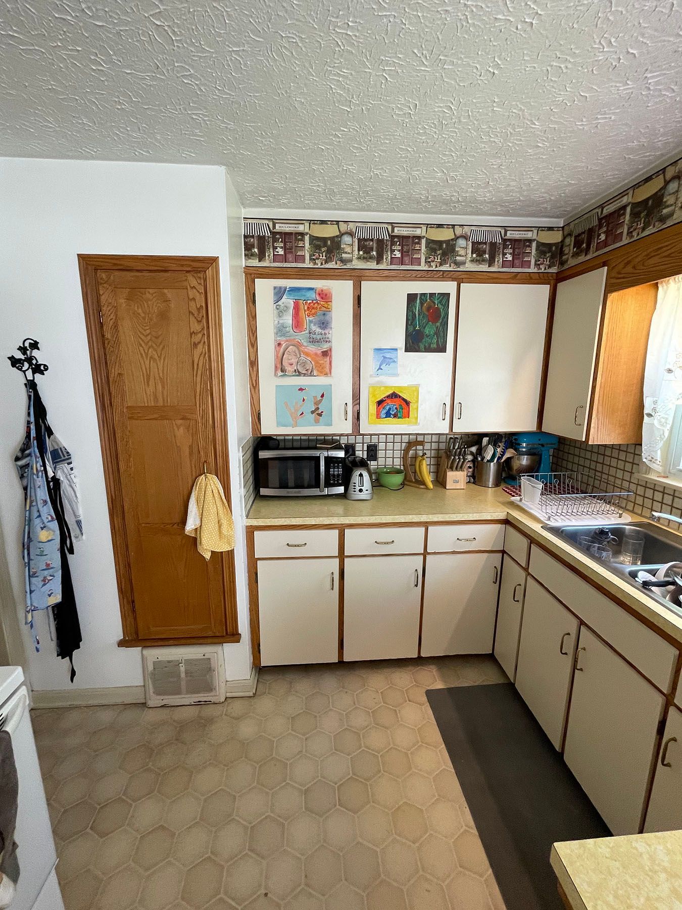 A kitchen with white cabinets a sink and a microwave