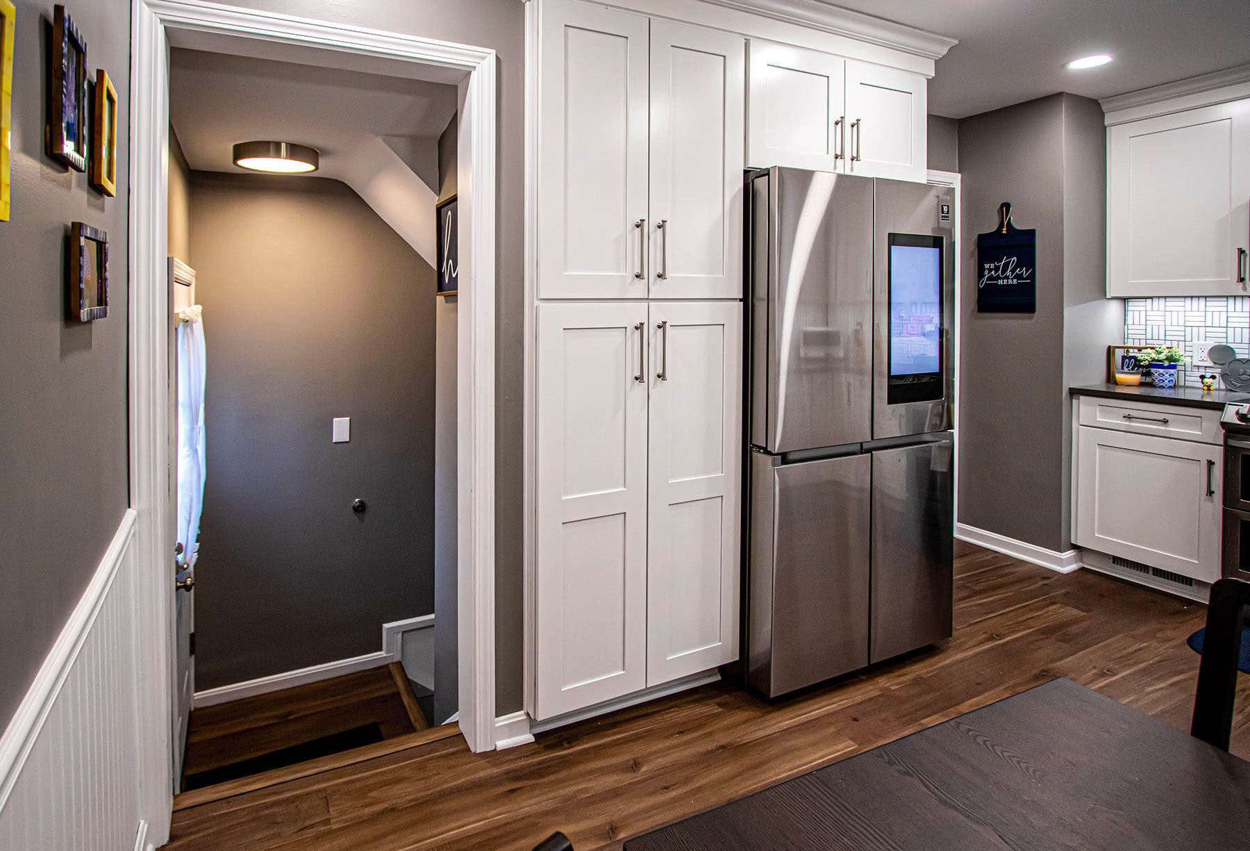 A kitchen with white cabinets and a stainless steel refrigerator.