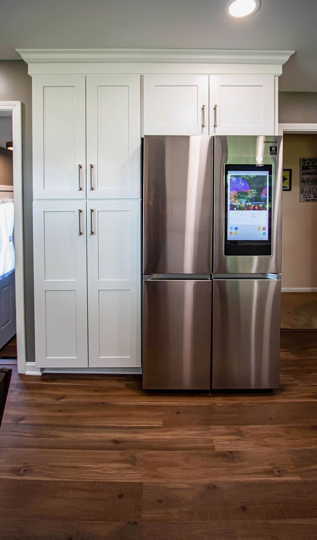 A stainless steel refrigerator with a screen on the door in a kitchen.