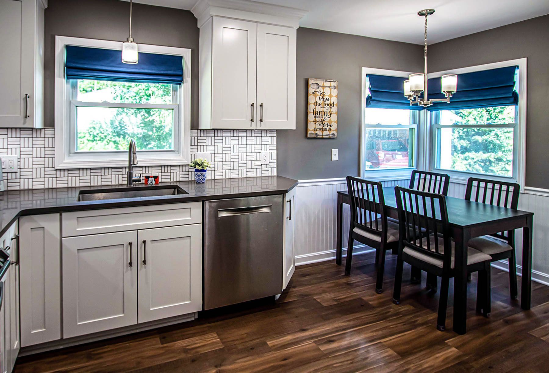 A kitchen with white cabinets , stainless steel appliances , a table and chairs.