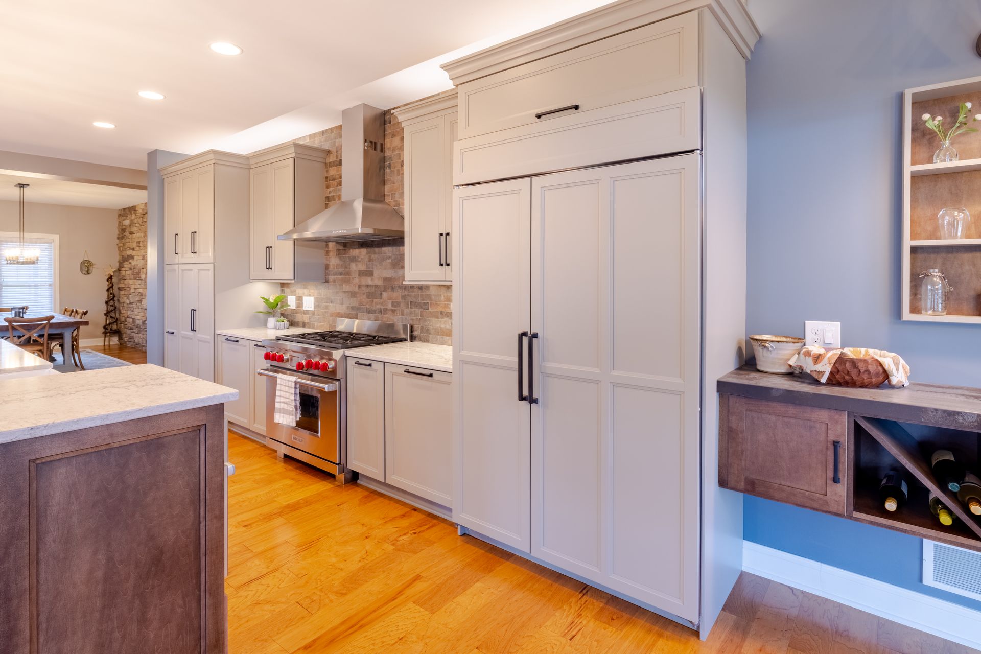 A kitchen with white cabinets , hardwood floors , stainless steel appliances and a wine rack.