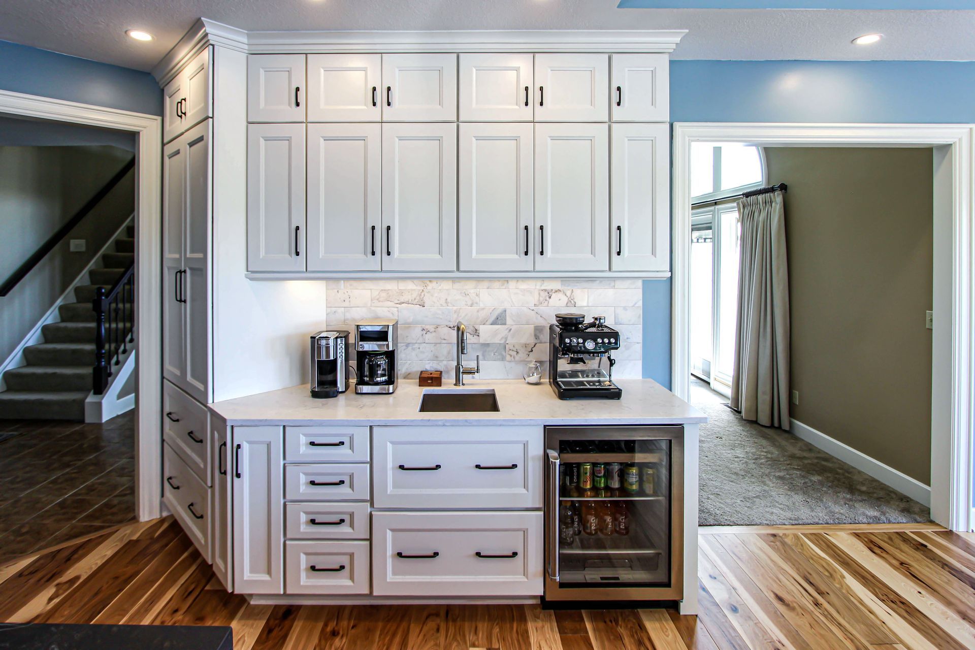A kitchen with white cabinets , a sink , a refrigerator and a coffee maker.