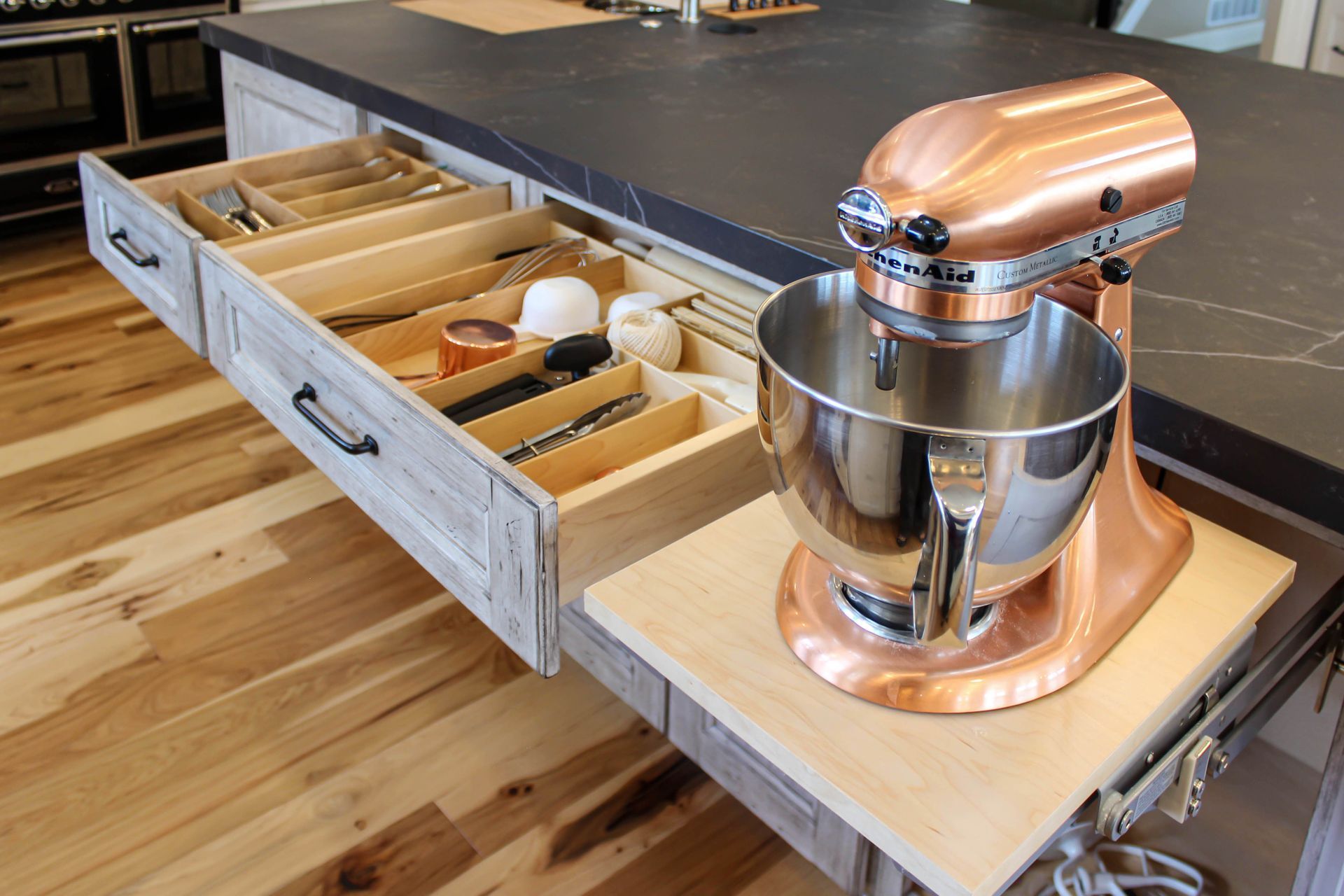 A kitchenaid mixer is sitting on top of a wooden shelf in a kitchen.