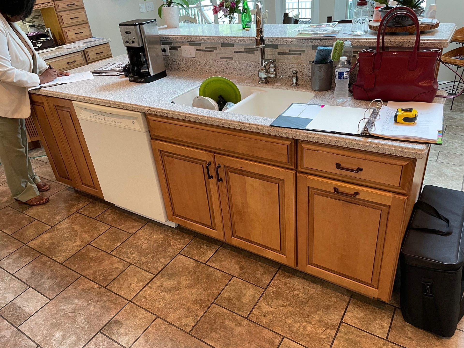 A woman is standing in a kitchen next to a sink.