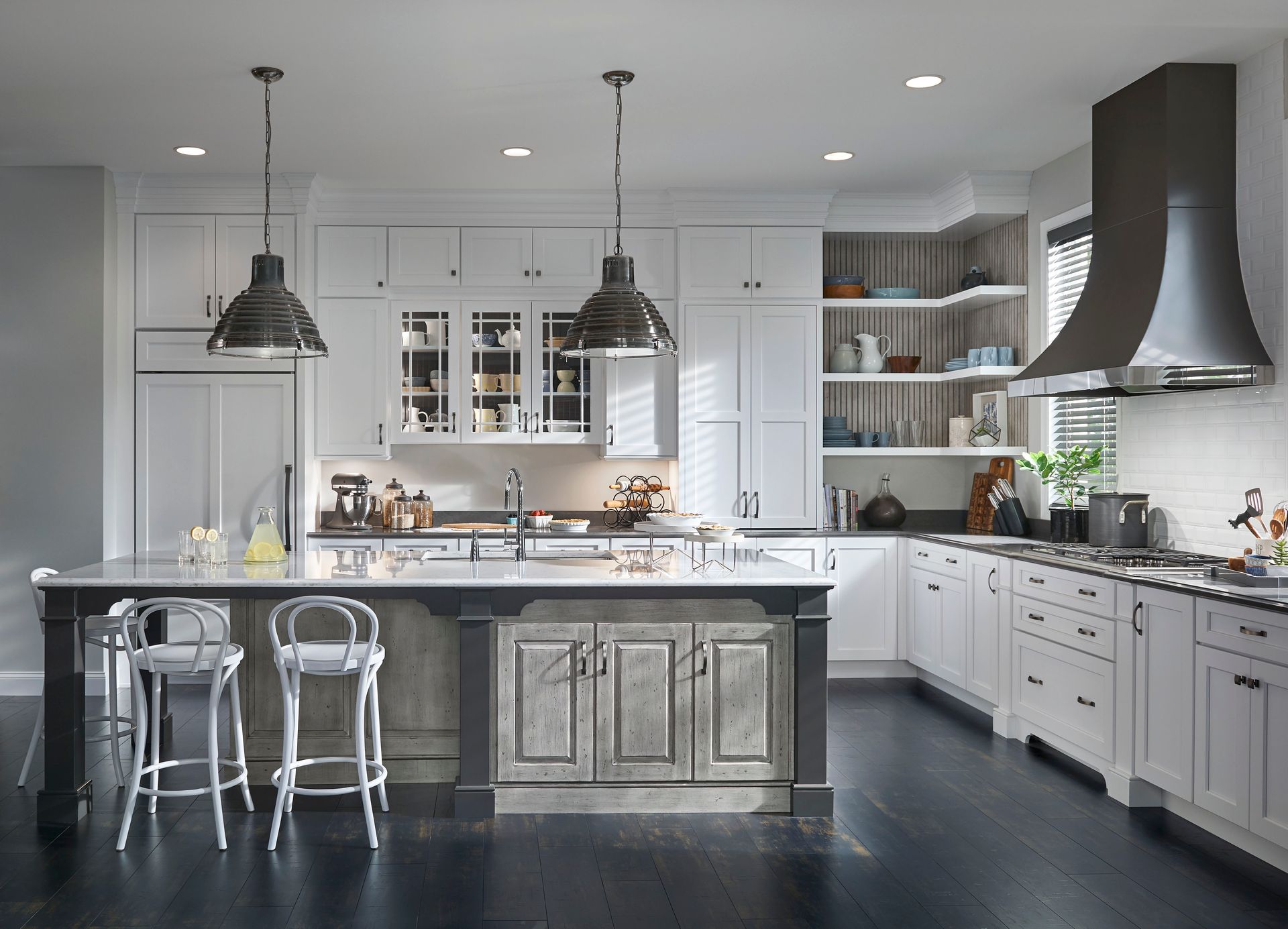 A kitchen with white cabinets , black counter tops , and a large island.