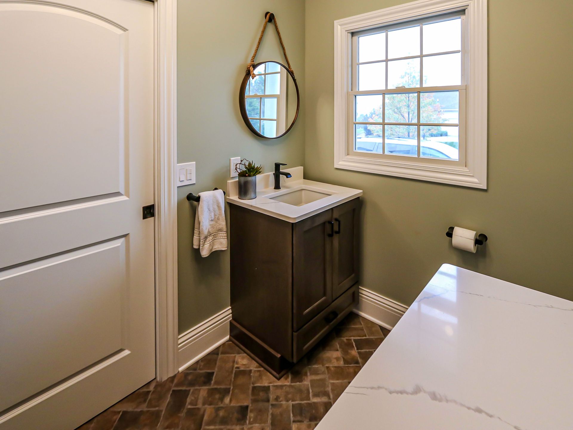 A bathroom with a sink , mirror and window.