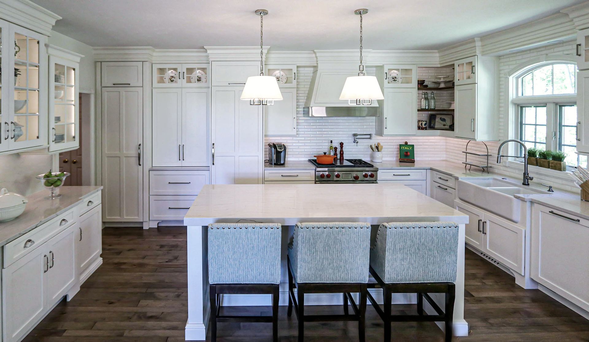 A kitchen with white cabinets and a large island in the middle.