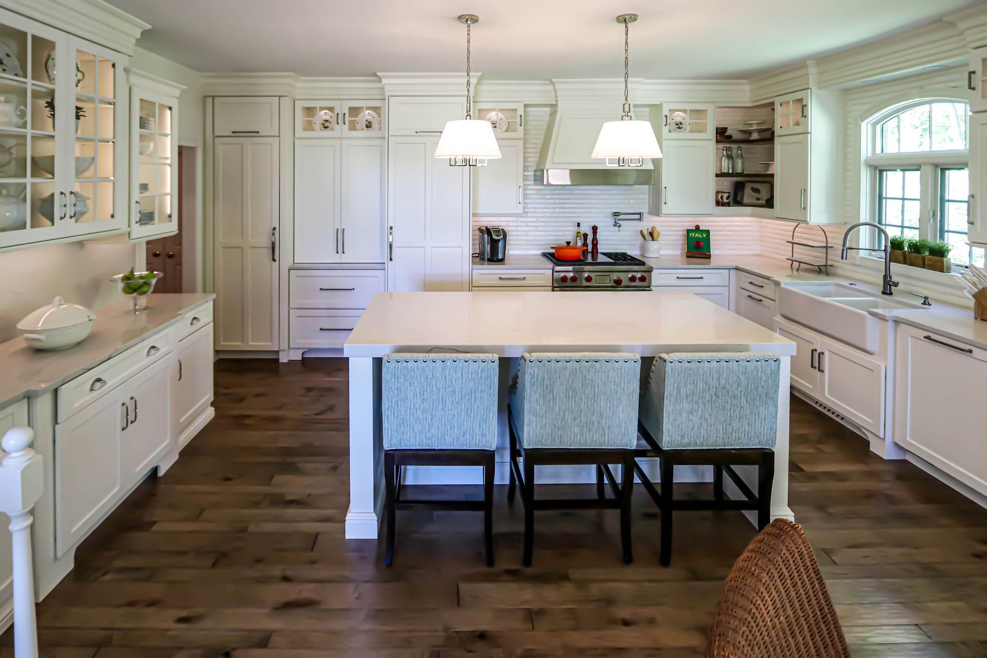 A kitchen with white cabinets and a large island in the middle