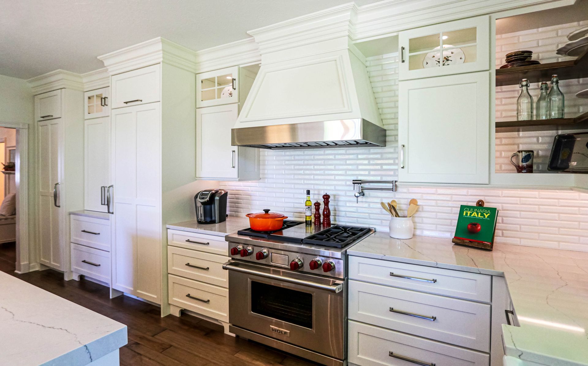 A kitchen with white cabinets , stainless steel appliances , and a pot on the stove.