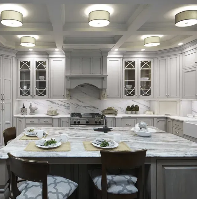 A kitchen with white cabinets and marble counter tops