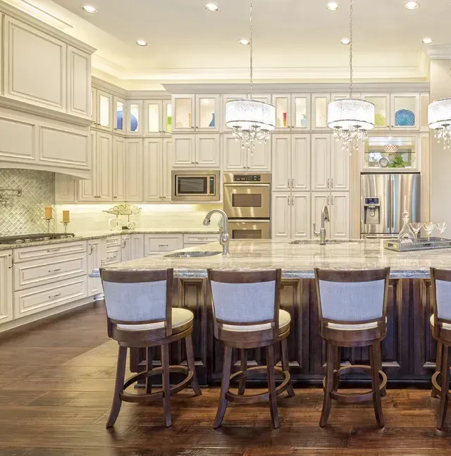 A kitchen with white cabinets , granite counter tops , stainless steel appliances and a large island.
