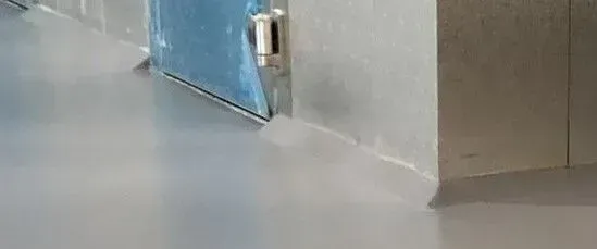 A close up of a door in a hallway with a gray floor.