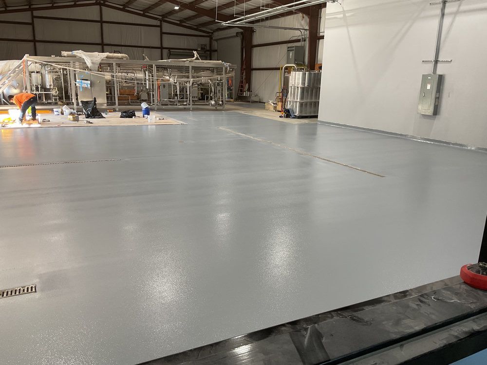 Gray resinous floor with trench drains in a beverage warehouse and distillery in Cumming, GA