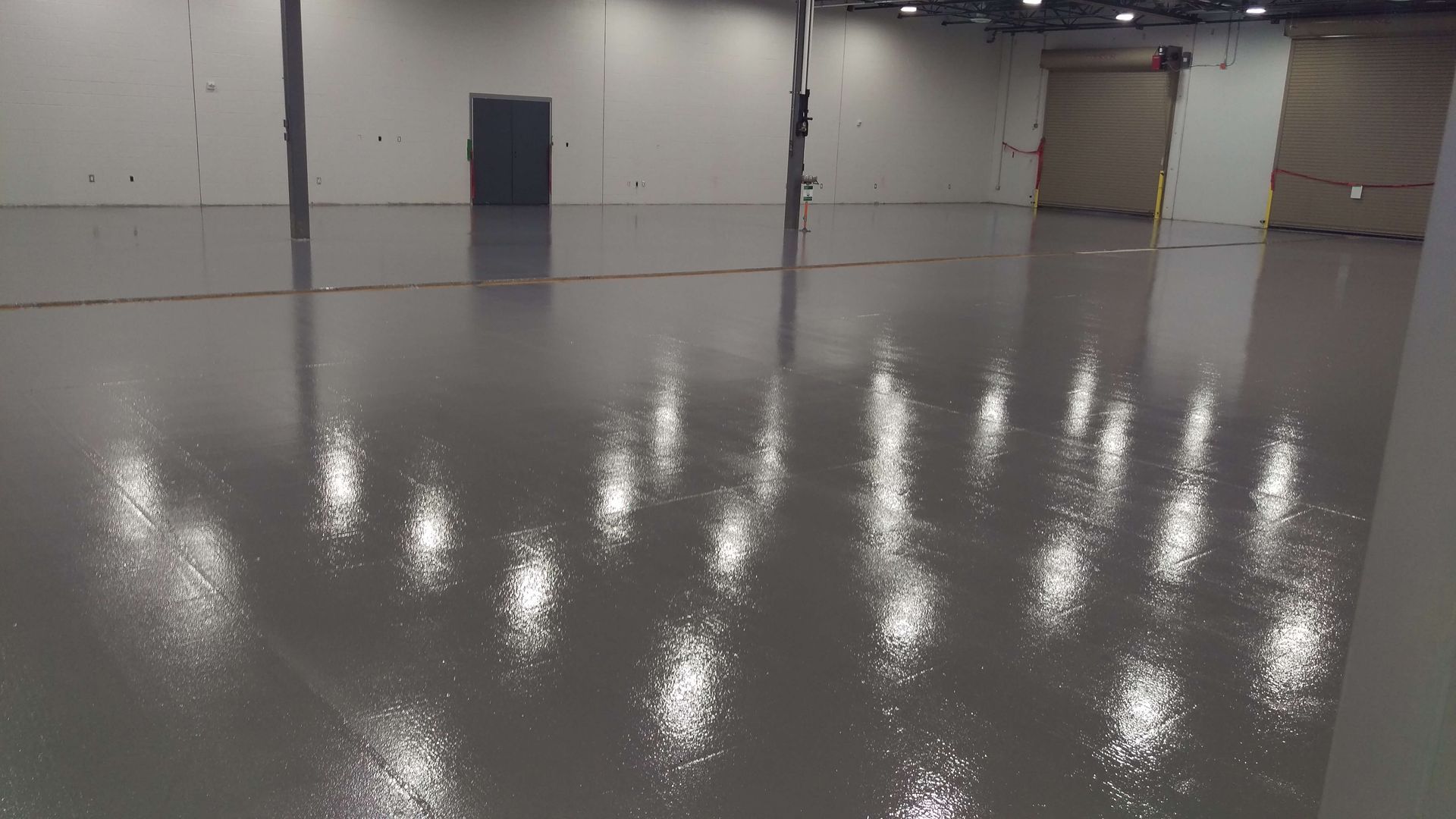 A large empty warehouse with a shiny floor and lots of lights.
