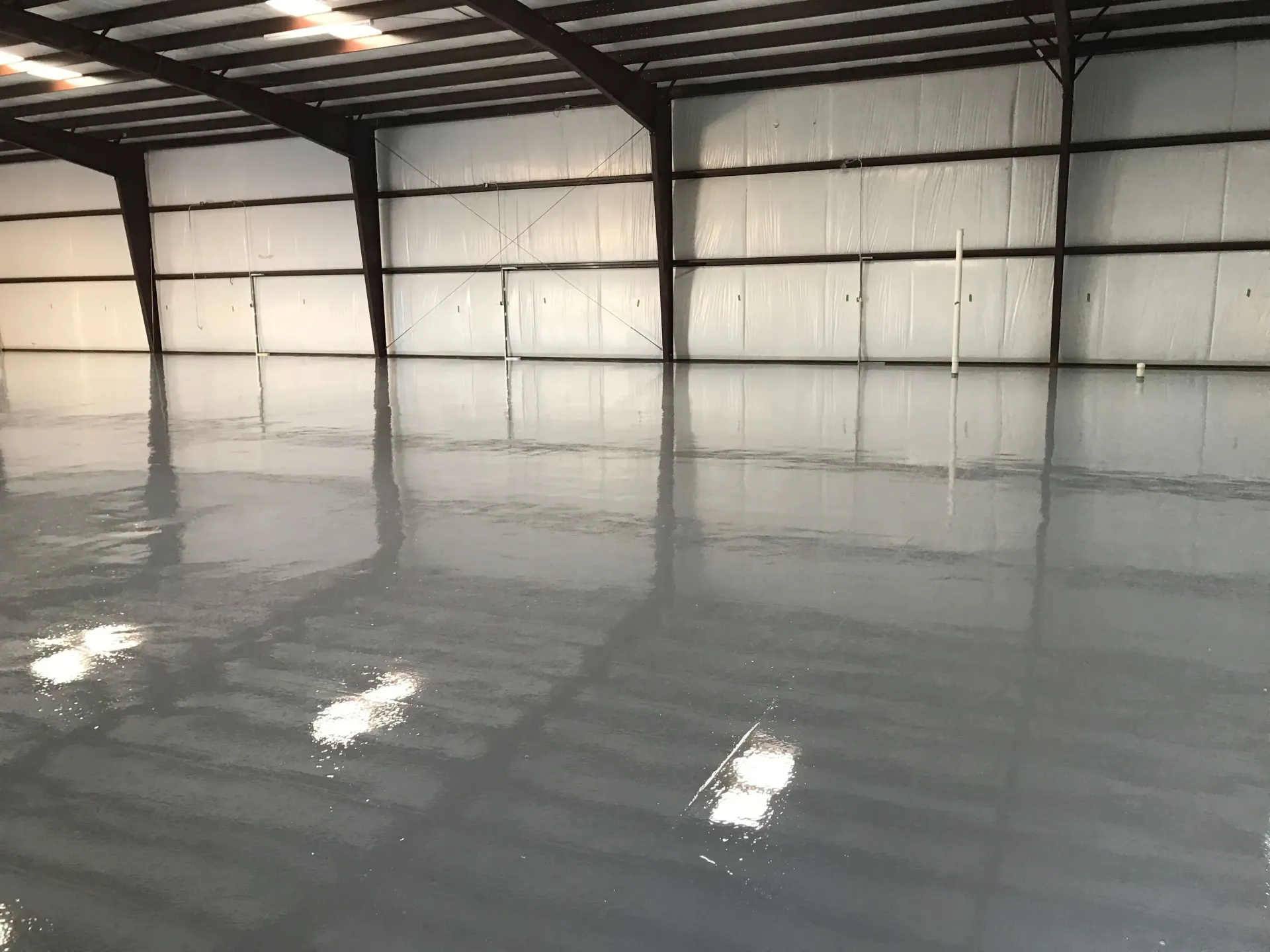 A large empty warehouse with a shiny concrete floor.