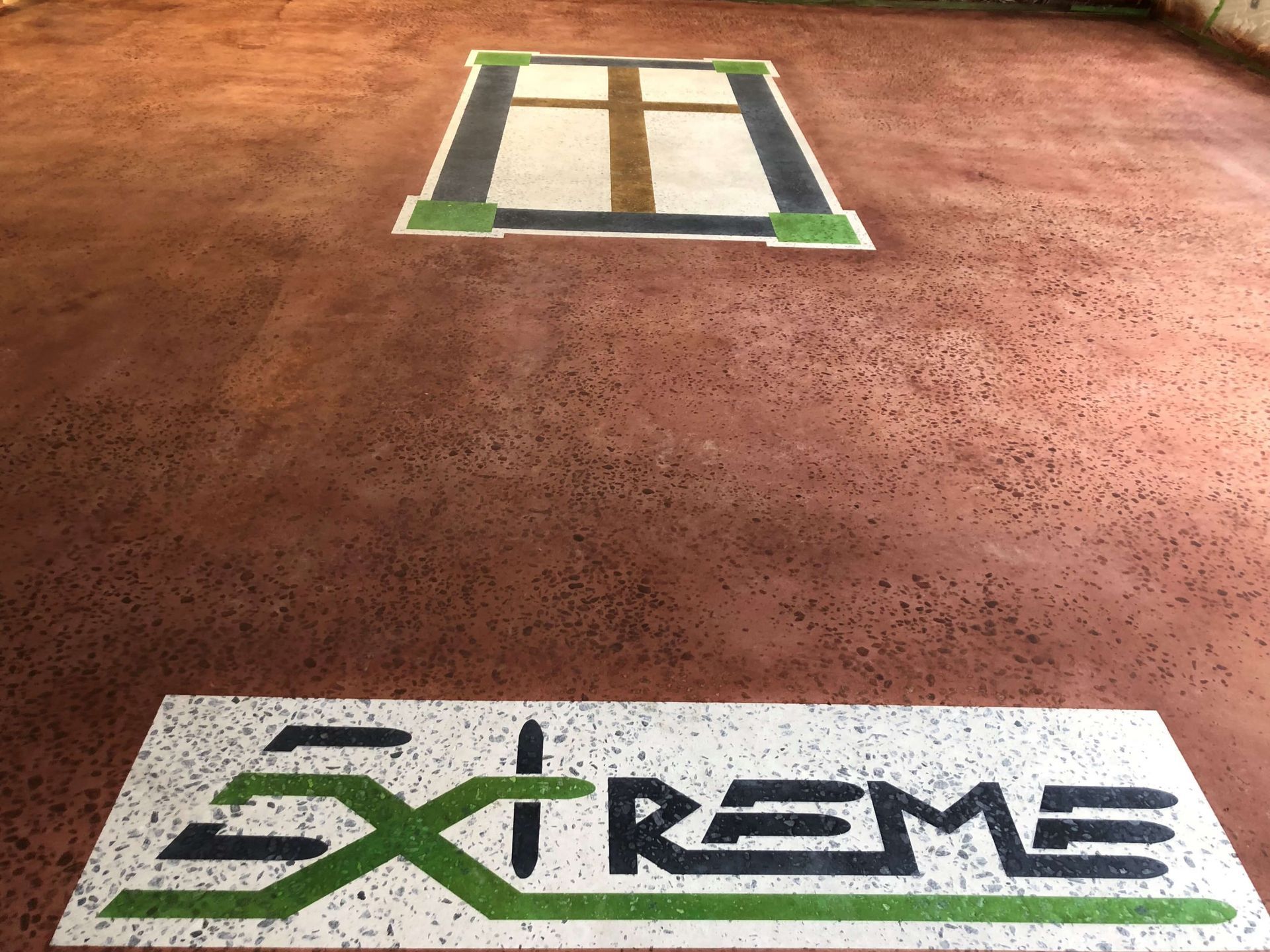 Textured brown floor with a green and white logo. A window-like pattern is centered above the logo.
