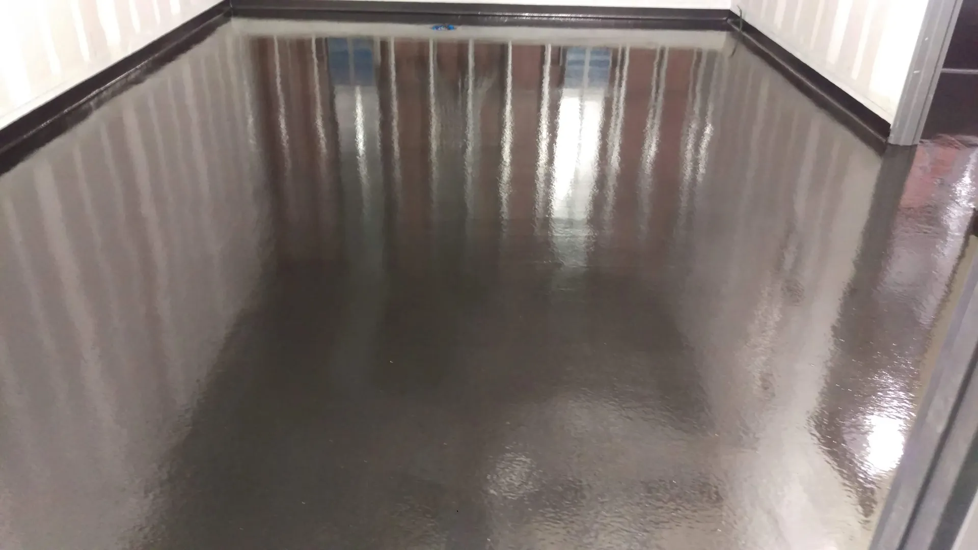 A room with a black floor and a white wall.