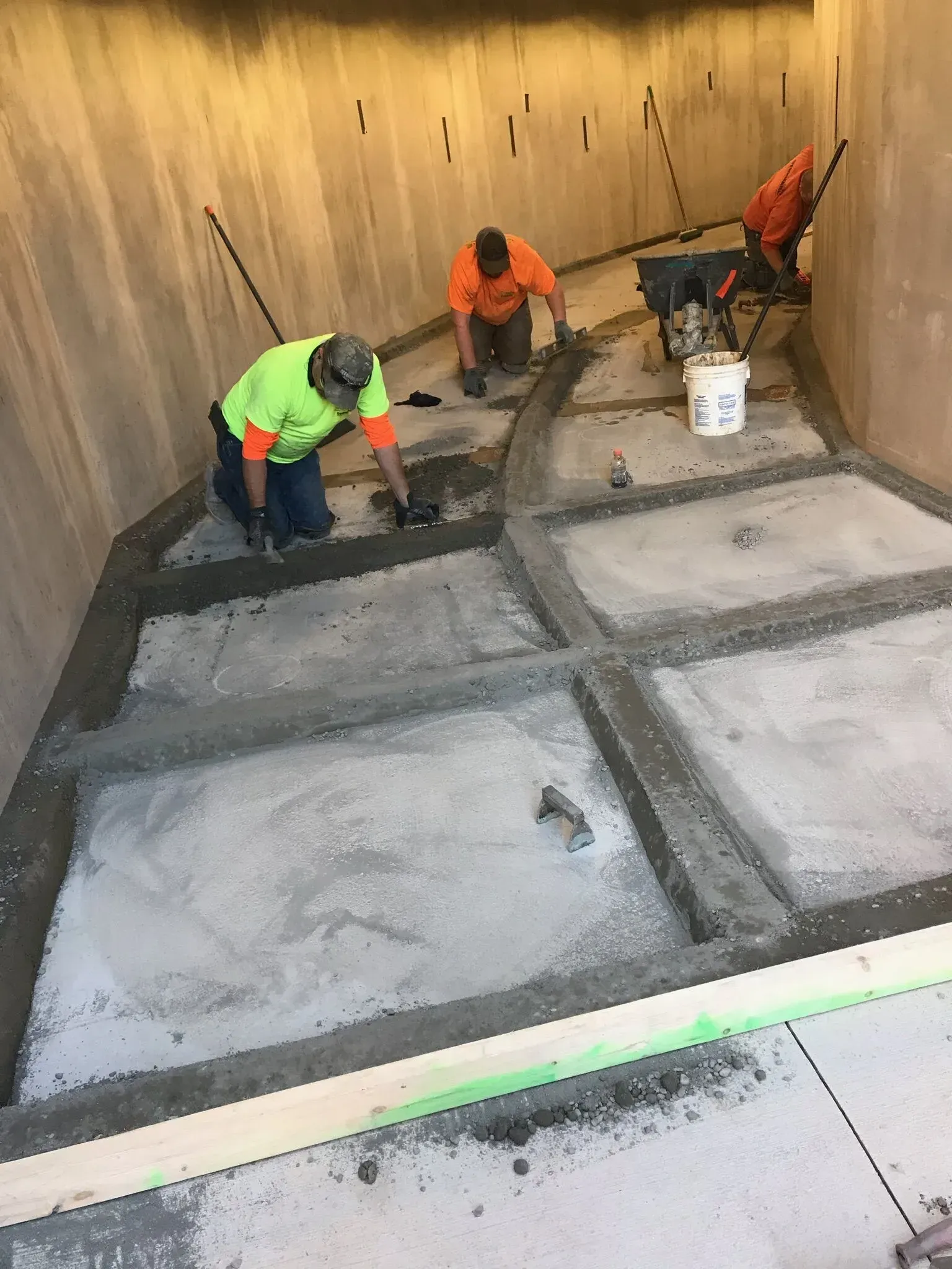 Two men are working on a concrete floor in a building.