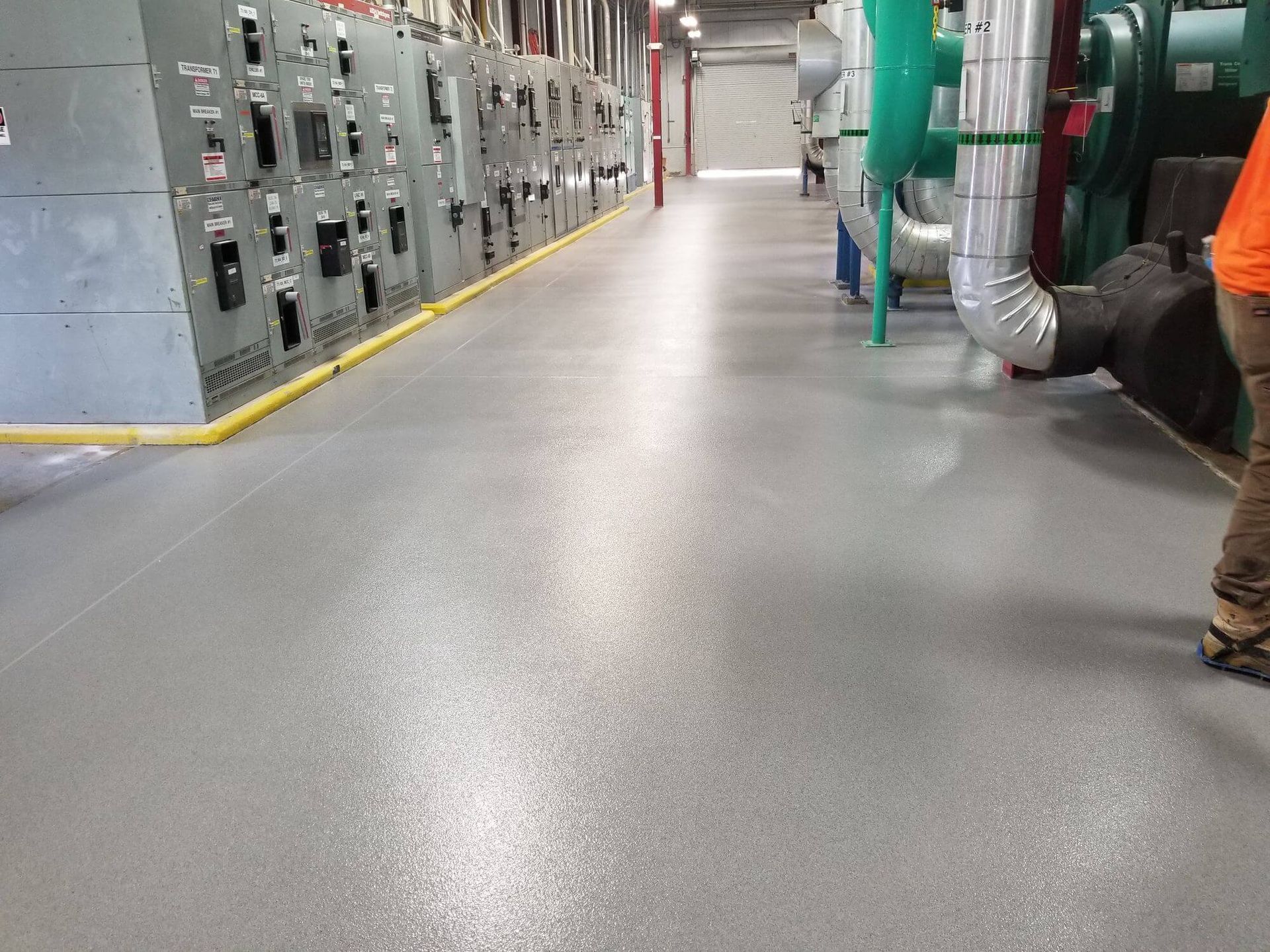 A man is standing in a large room with a gray floor.