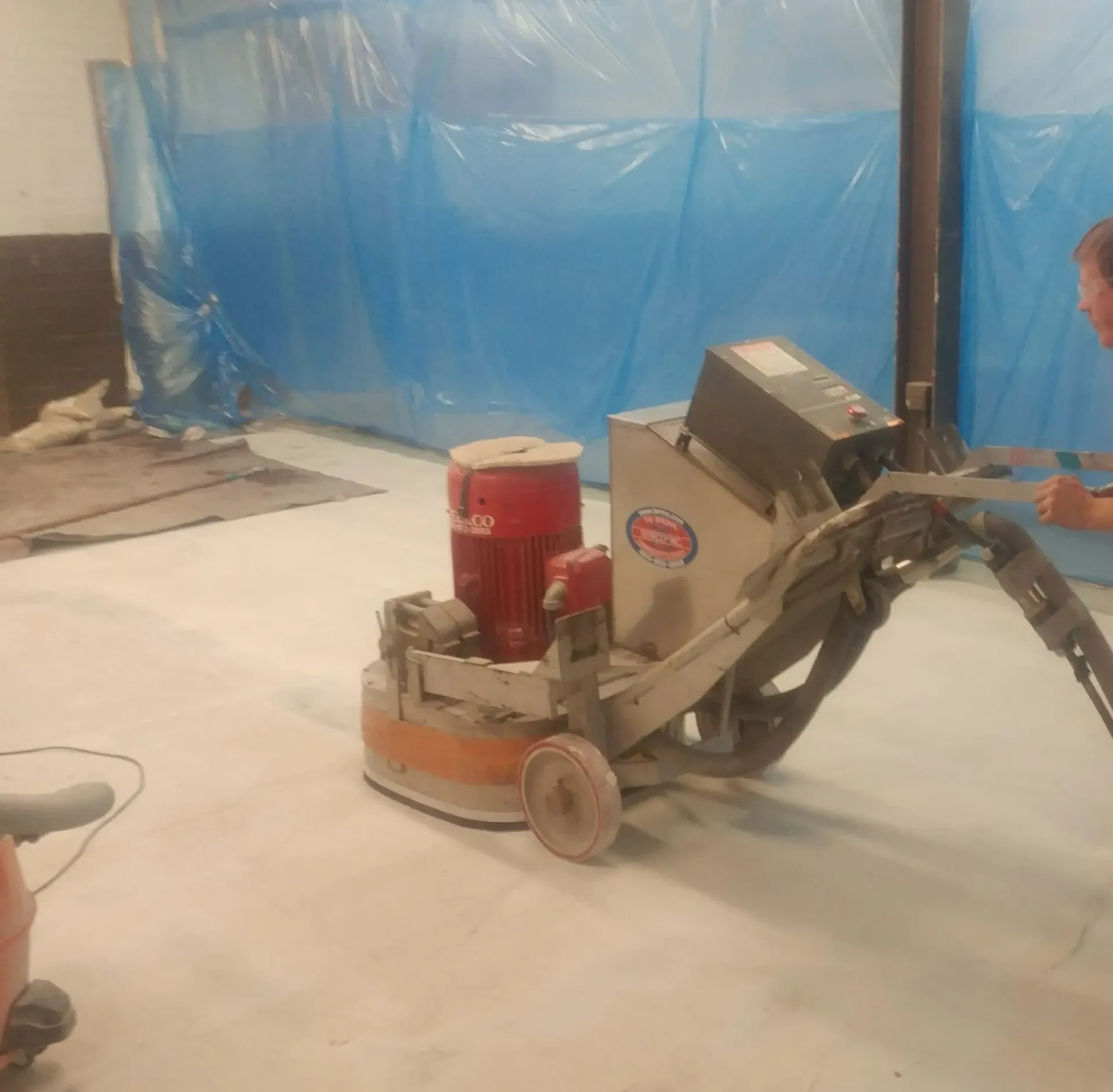 A man is using a machine to polish a concrete floor.