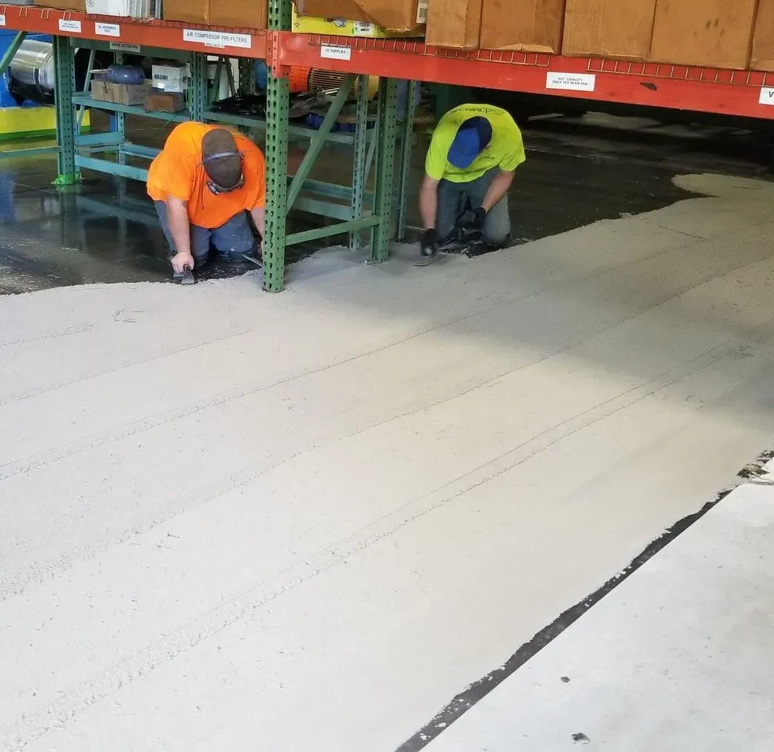 Two men are working on a floor in a warehouse