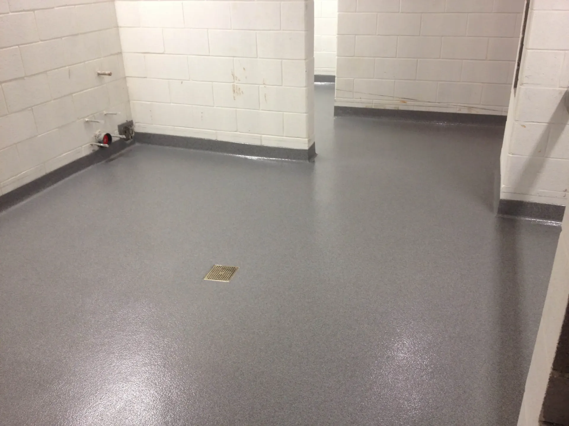 A room with a gray floor and white brick walls.