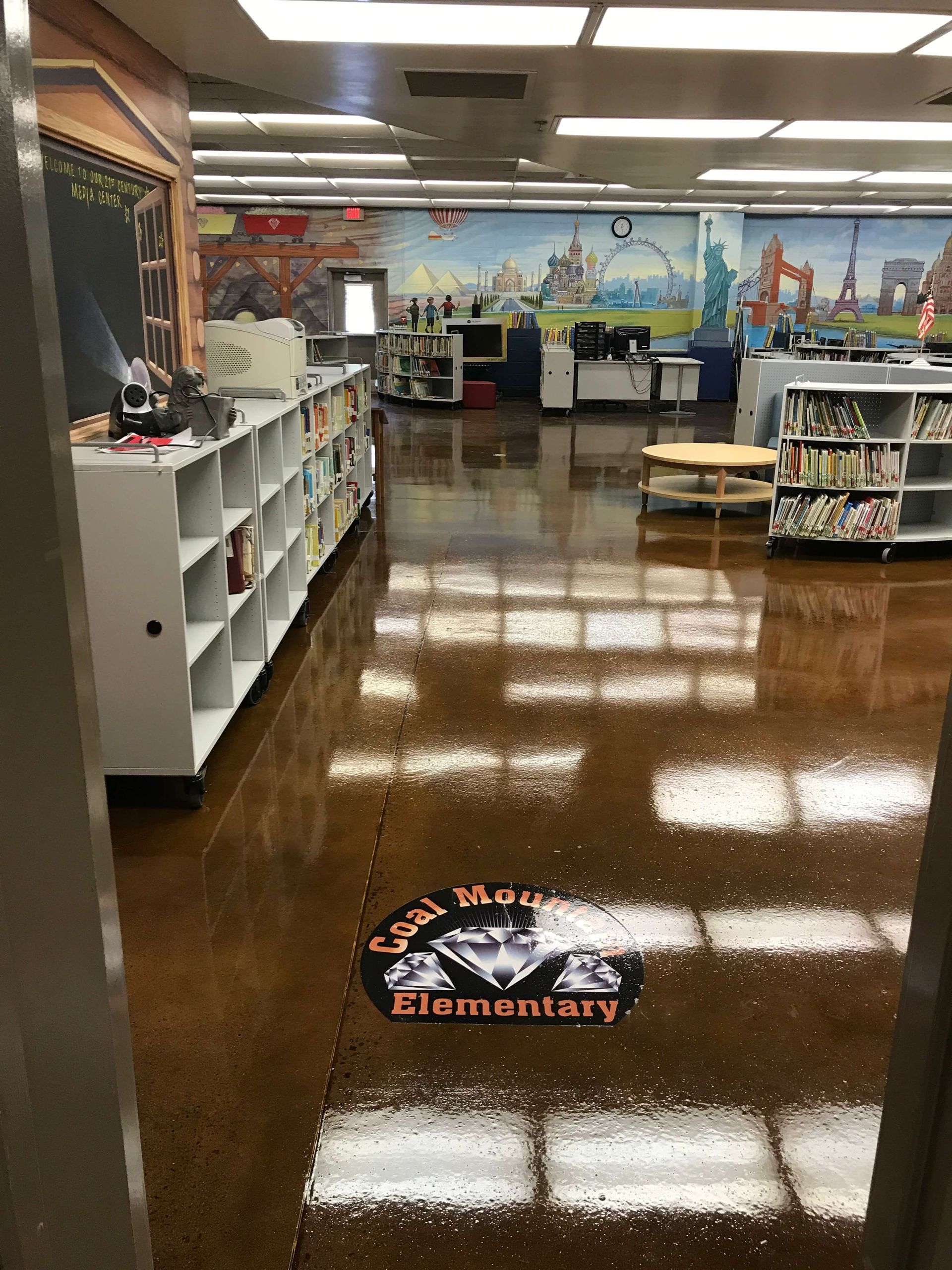 A library with a painting on the wall and a logo on the floor.