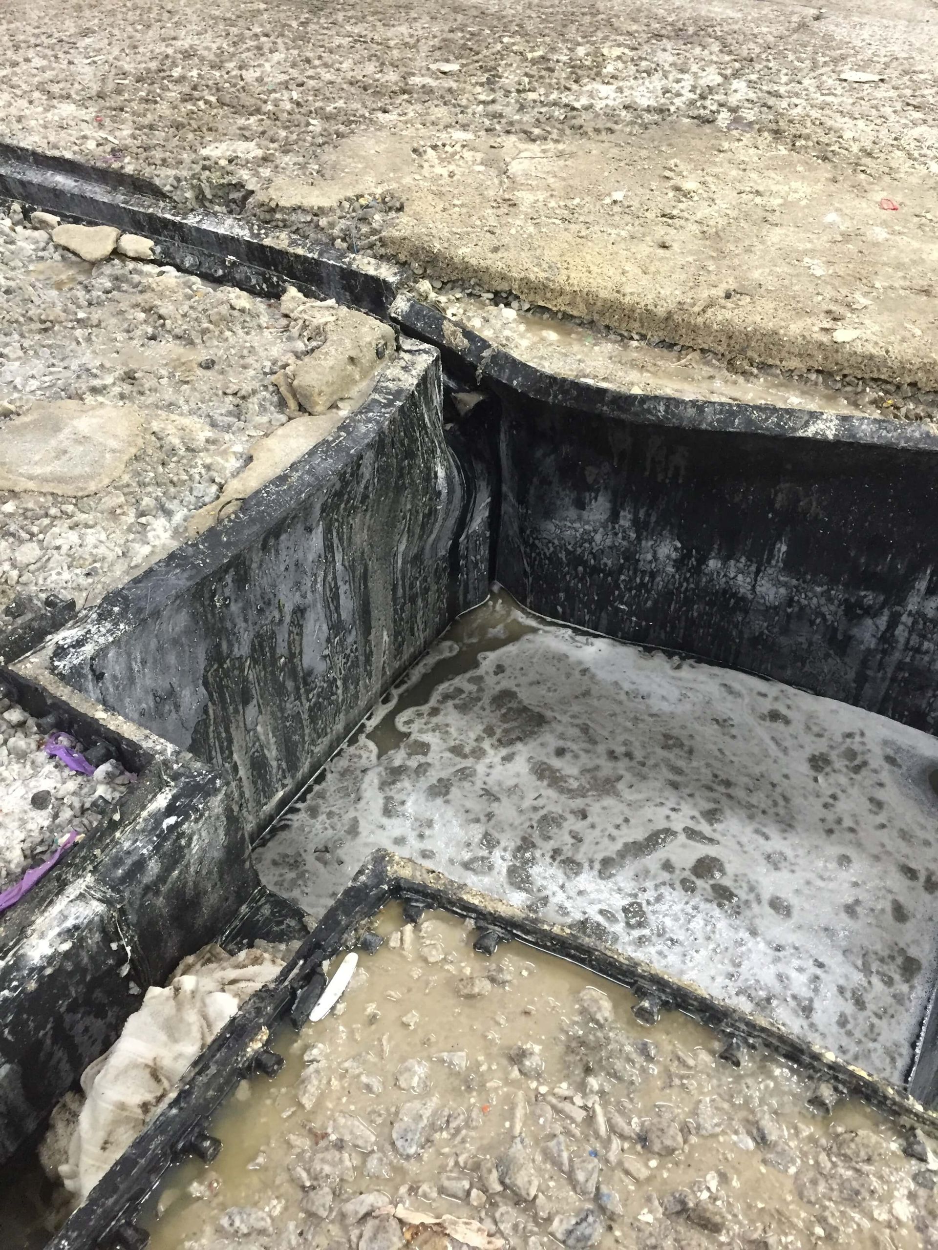 A close up of a hole in the ground filled with water.