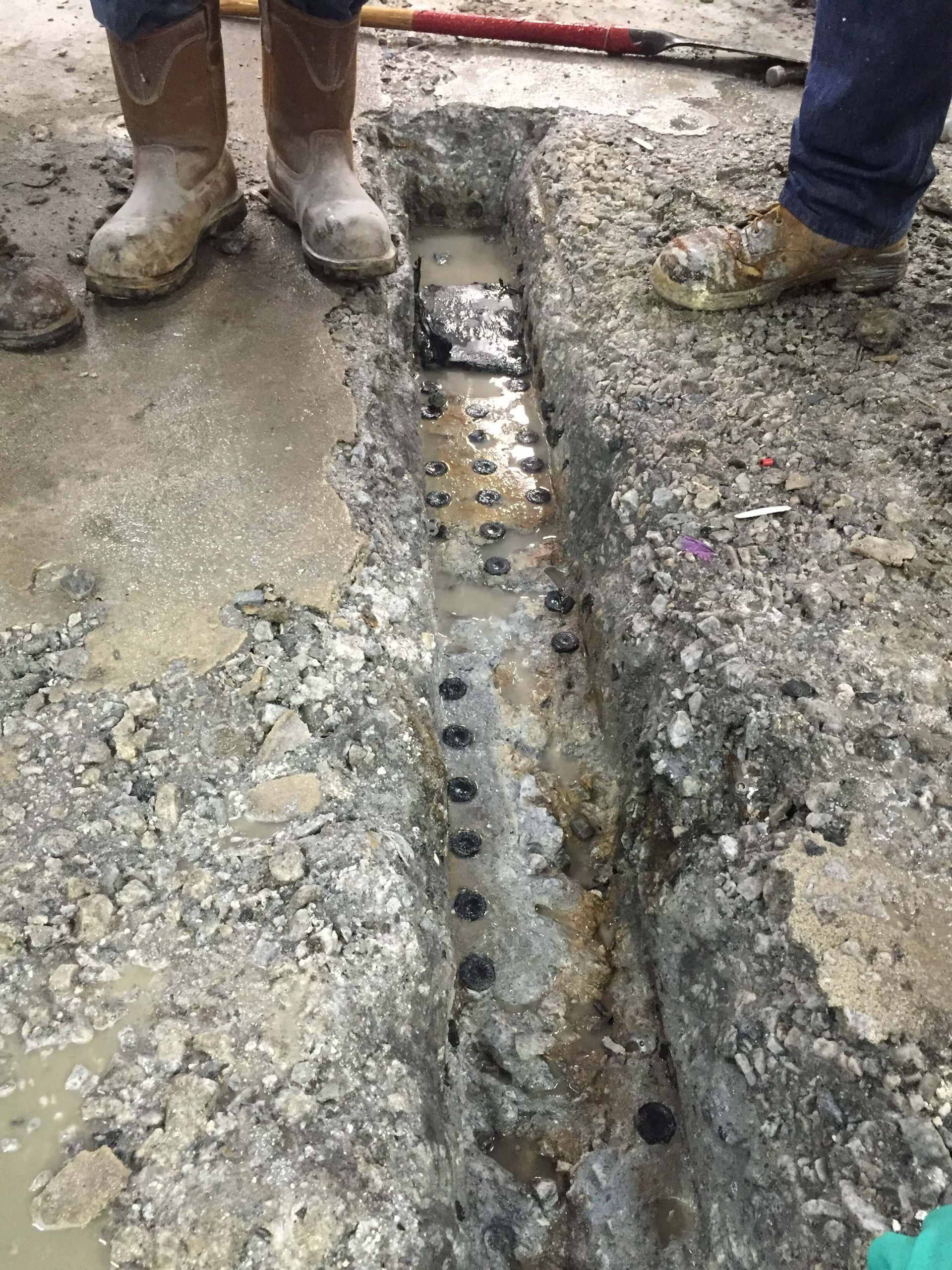 A person wearing cowboy boots is standing next to a hole in the ground.