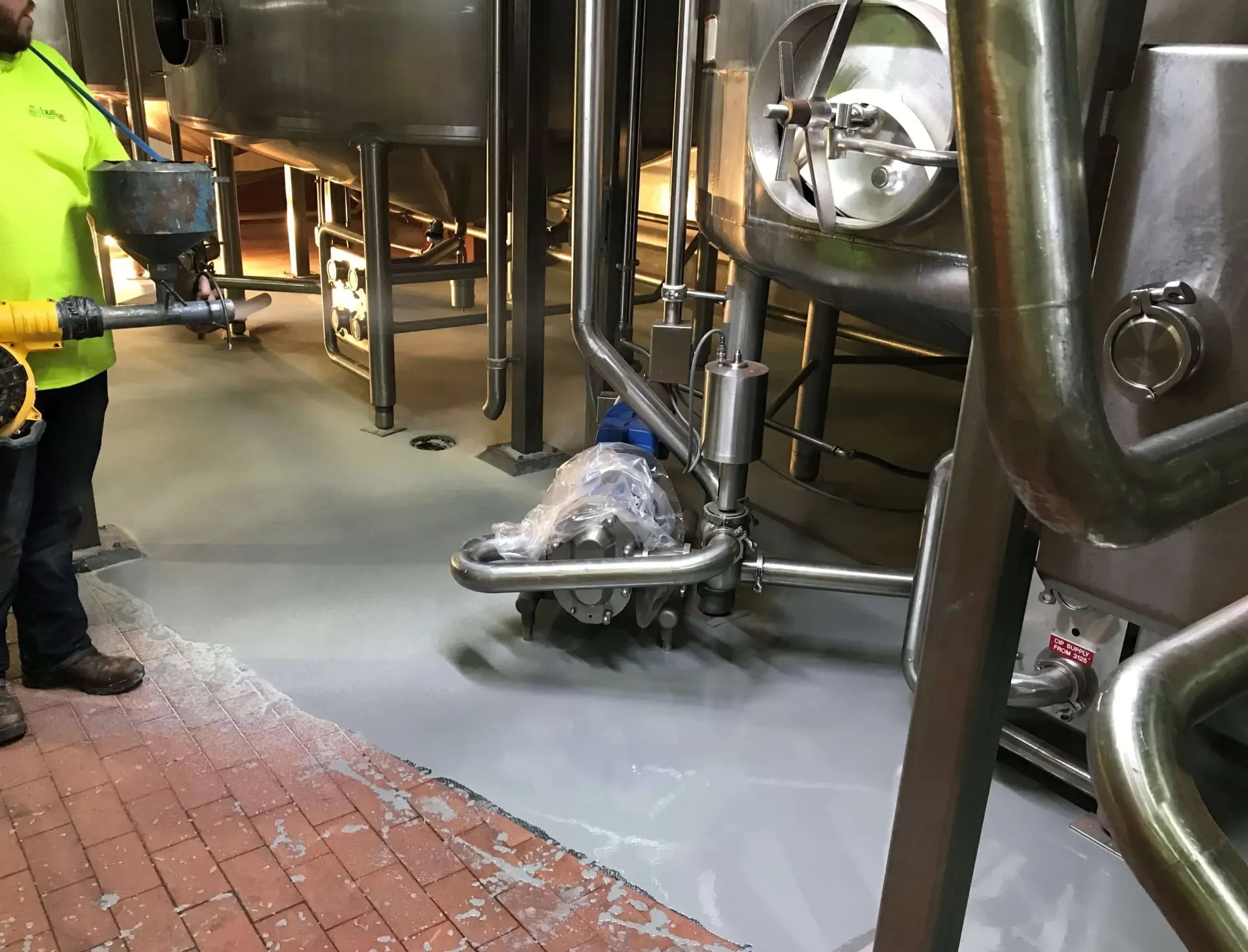 A man is standing in a factory holding a vacuum cleaner.