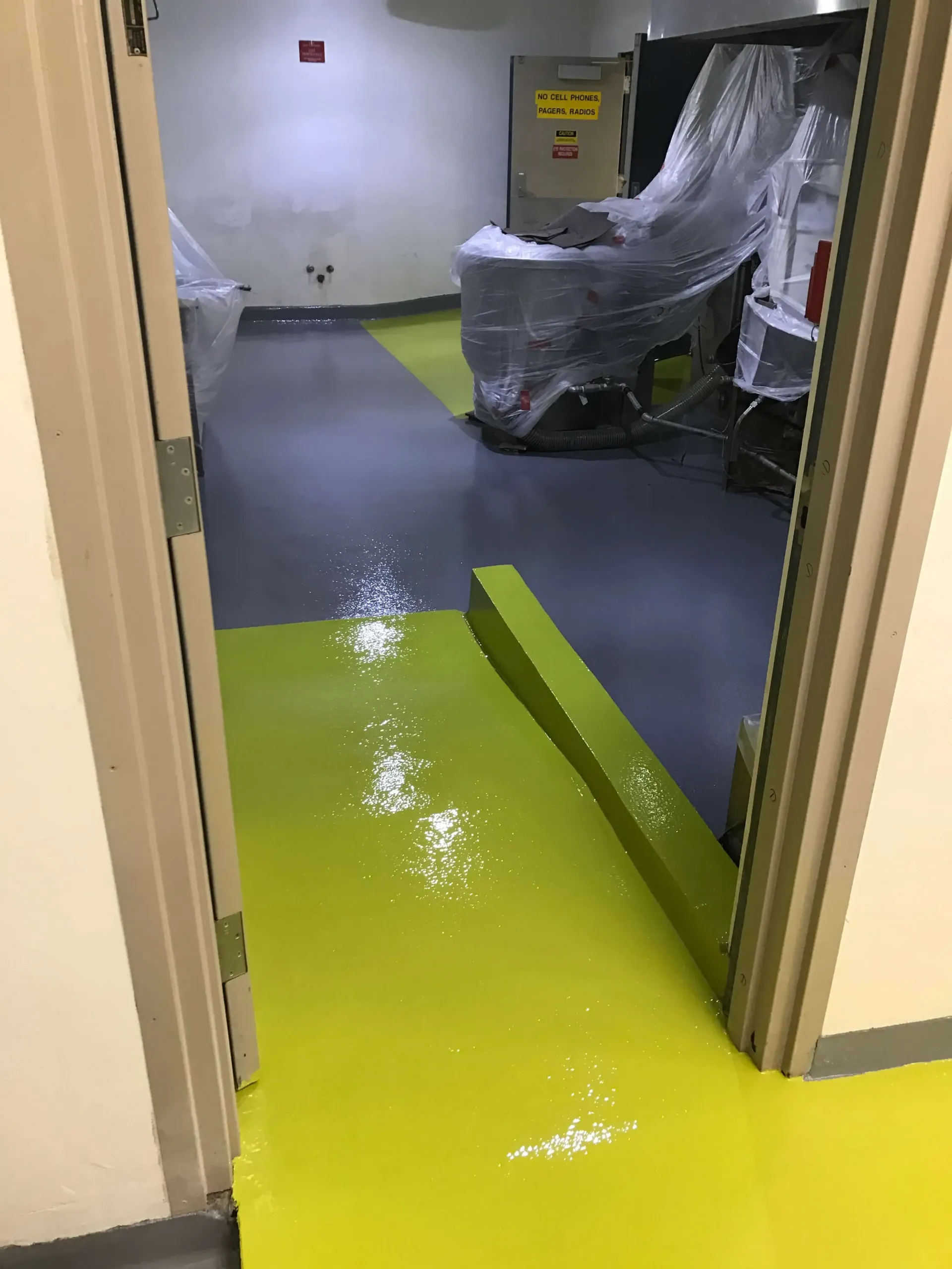 A hallway with a yellow floor and a chair wrapped in plastic.